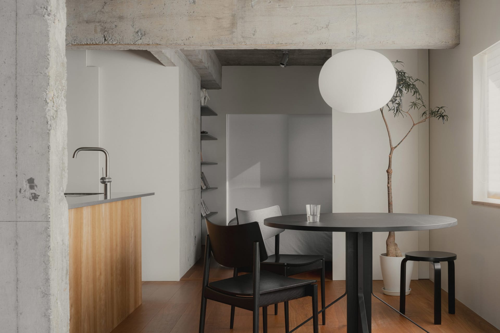 Modern minimalist living room with a concrete floor and minimalist decor, featuring a round dining table and chairs, and a mi