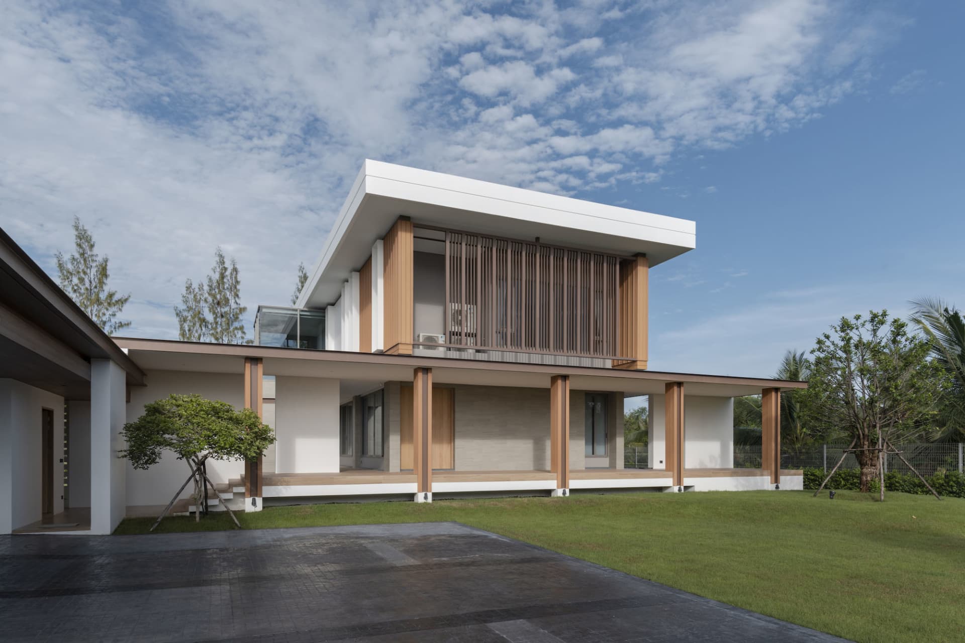 A modern villa with a rendered concrete exterior and large overhanging roof.