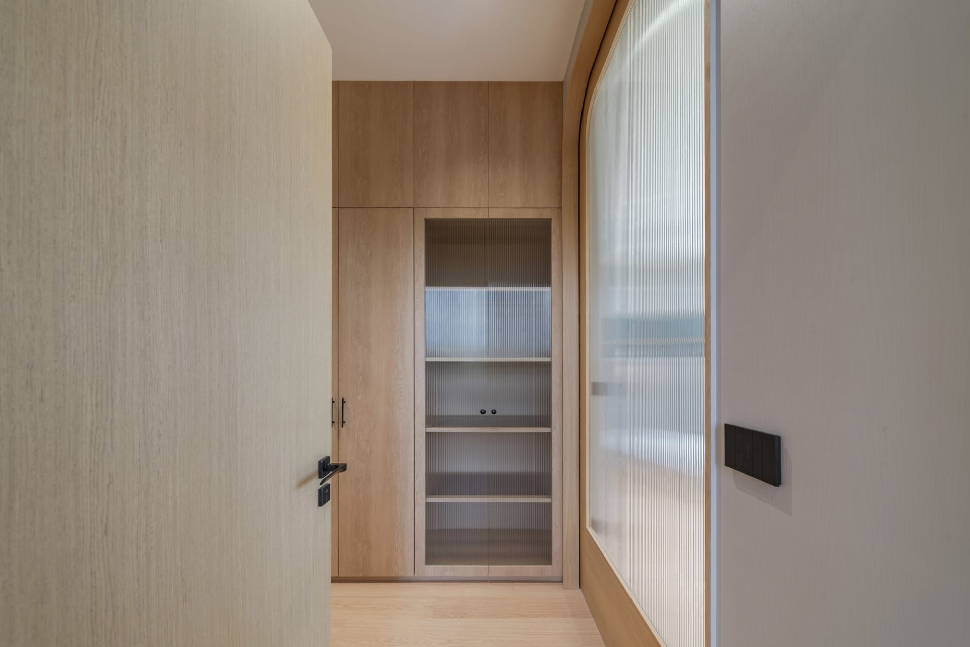 Modern wooden wardrobe with glass doors and wooden shelves.