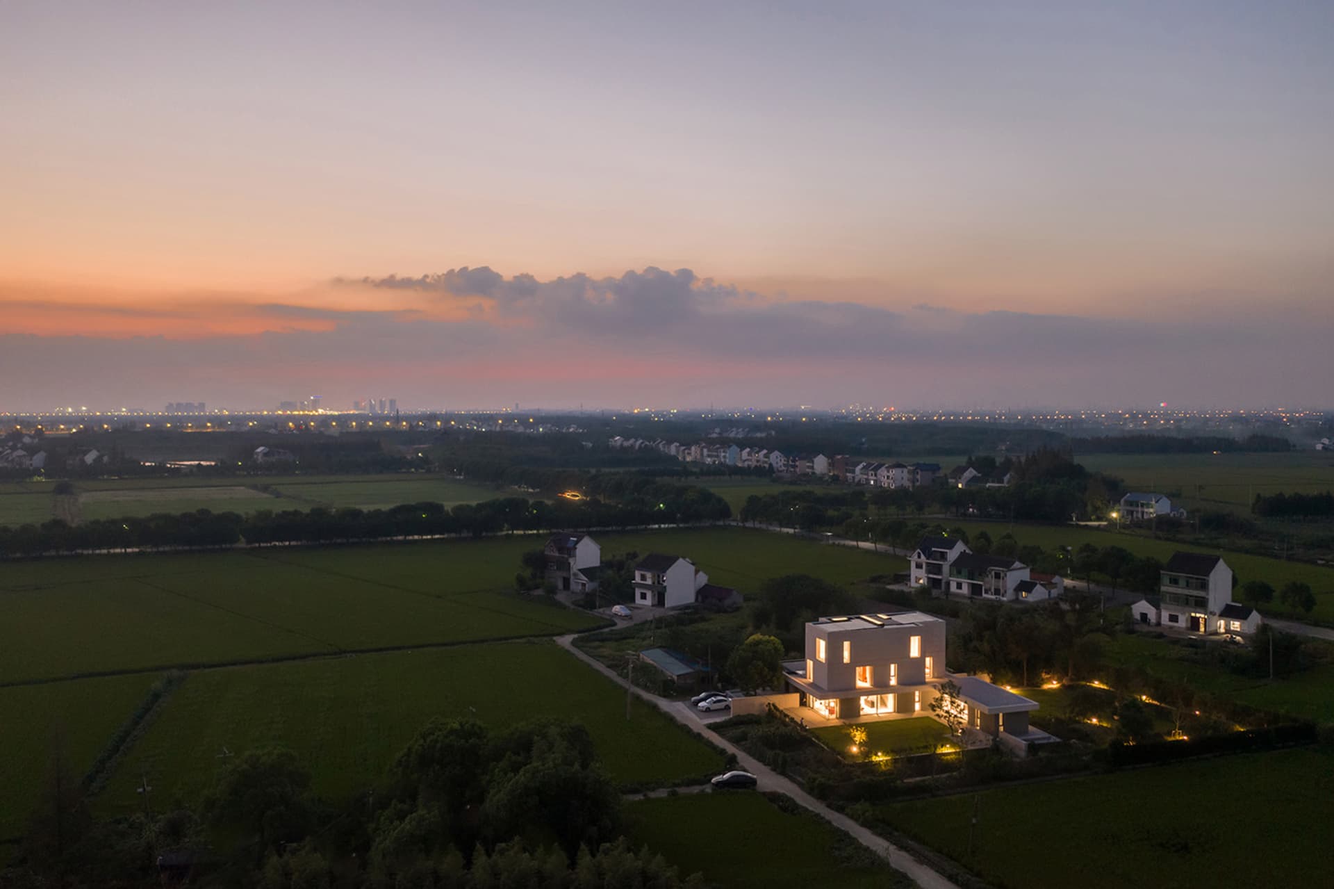 俯瞰鄉村生活空間，現代建築與夕陽天空為背景。