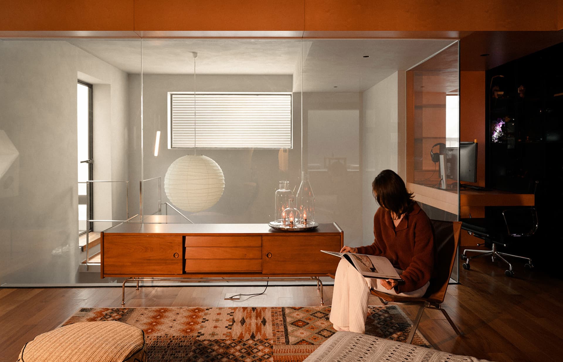 A modern living room with wood flooring, glass coffee table, and fabric seating.