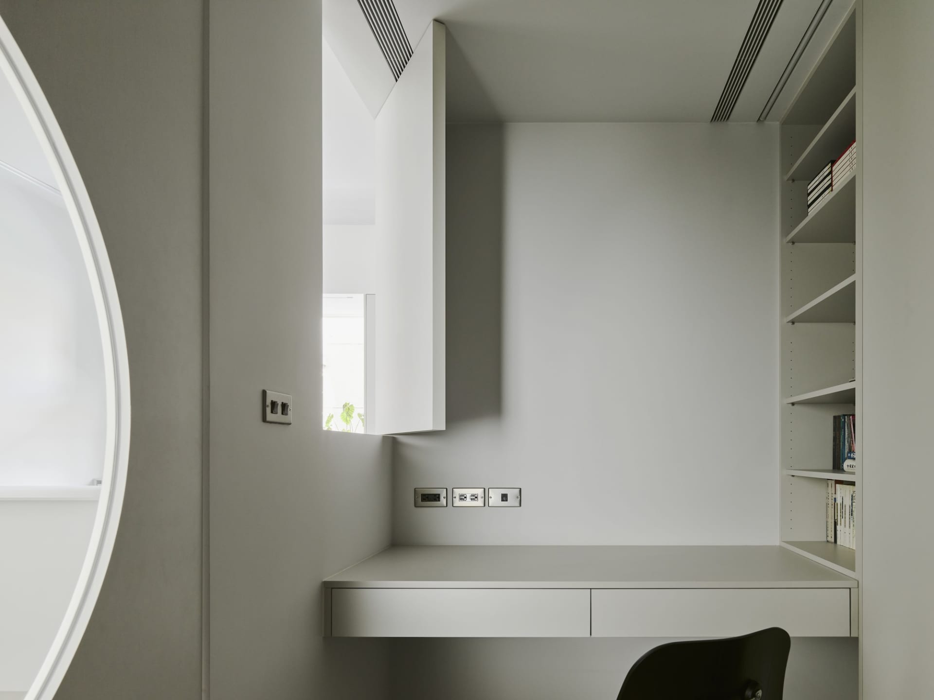 A modern minimalist home office with a floating desk, white walls, and a minimalist chair.