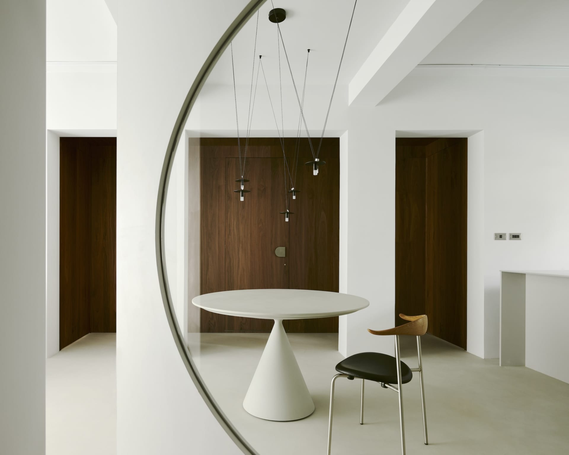 Modern white dining room with concrete floor, minimalist design, and aconic table.