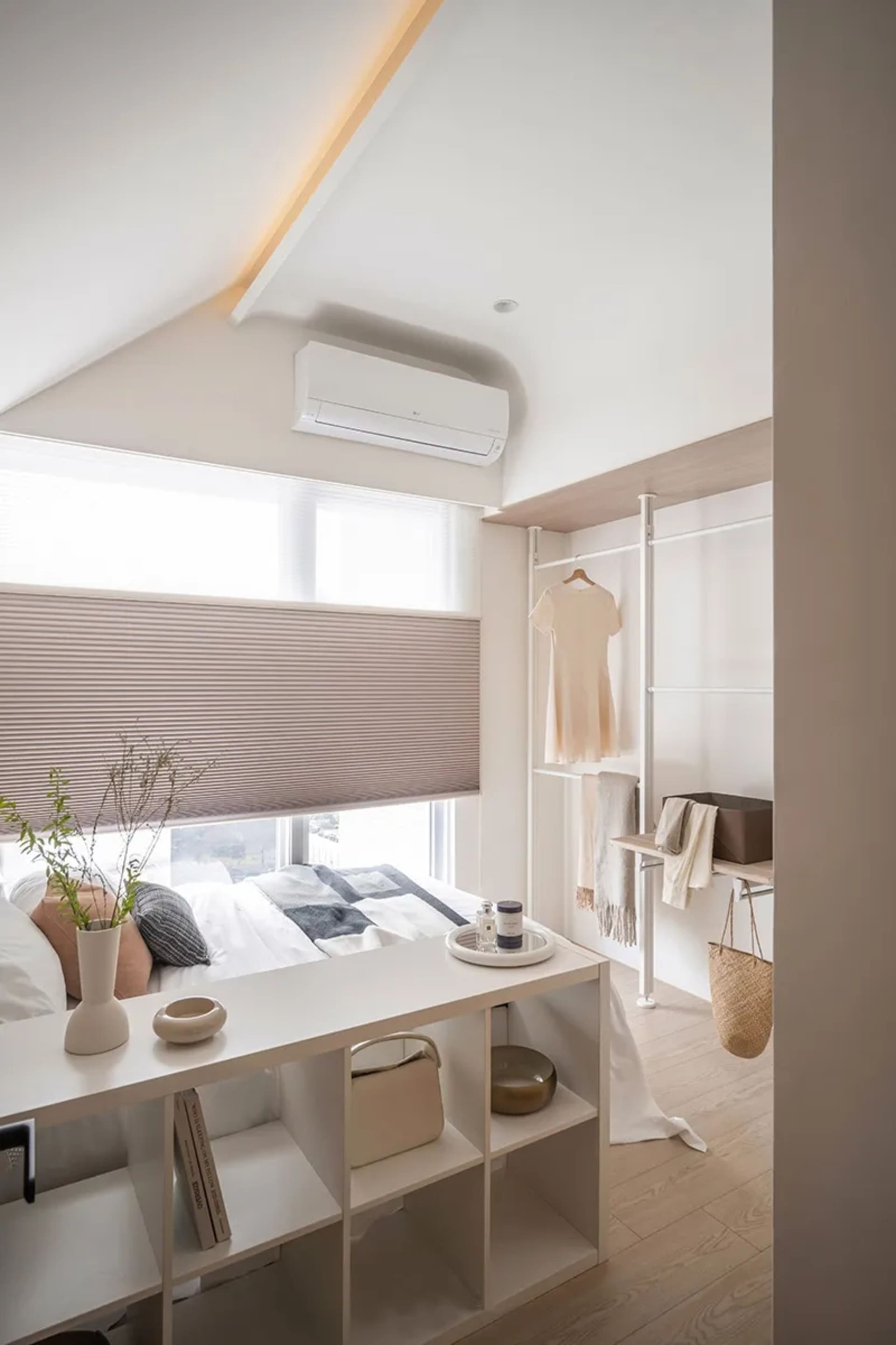 A minimalist bedroom with wooden furnishings, a bed, a desk, and organized closet space.