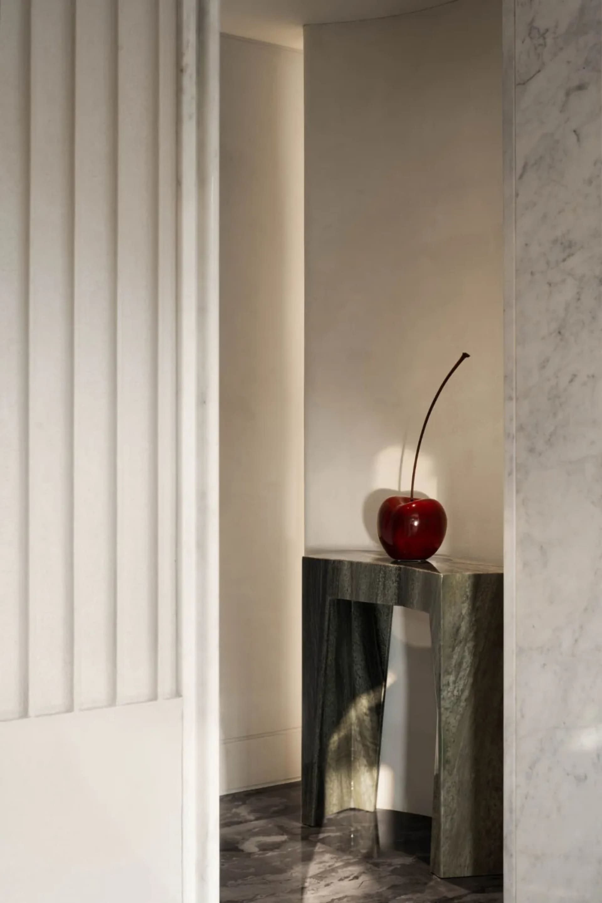 A modern interior setting featuring a marble table with a red cherry on it.