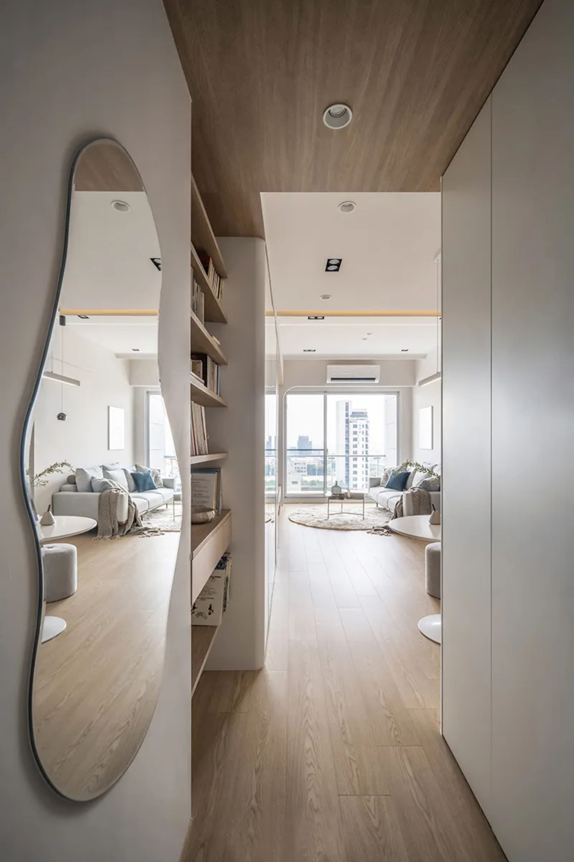 A modern living room featuring wooden flooring, minimalist furniture, and a balcony view.