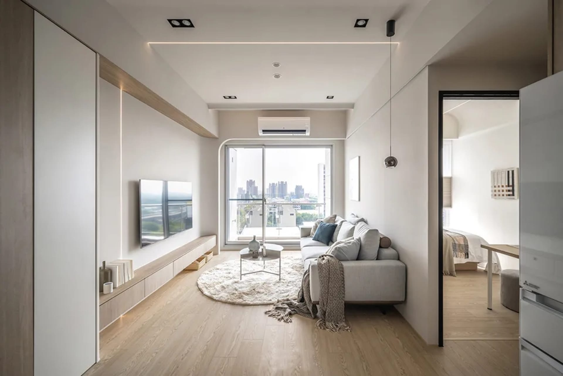 A modern living space with white painted walls and a large window overlooking a cityscape.