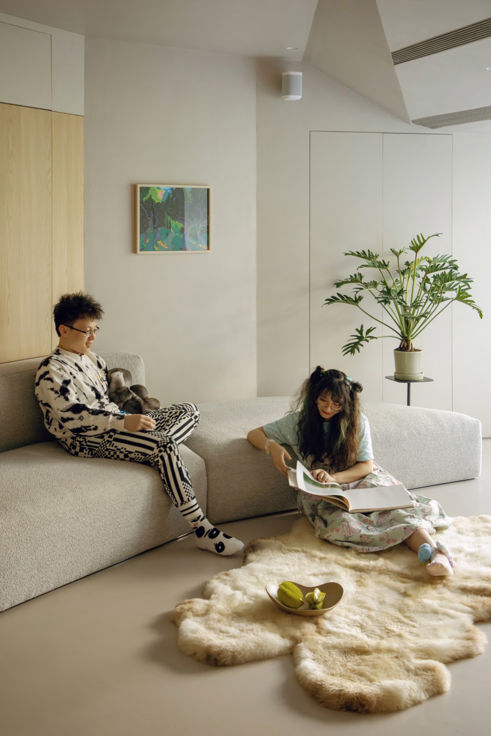 A modern minimalist living room with concrete walls, leather furniture, and plush textiles.