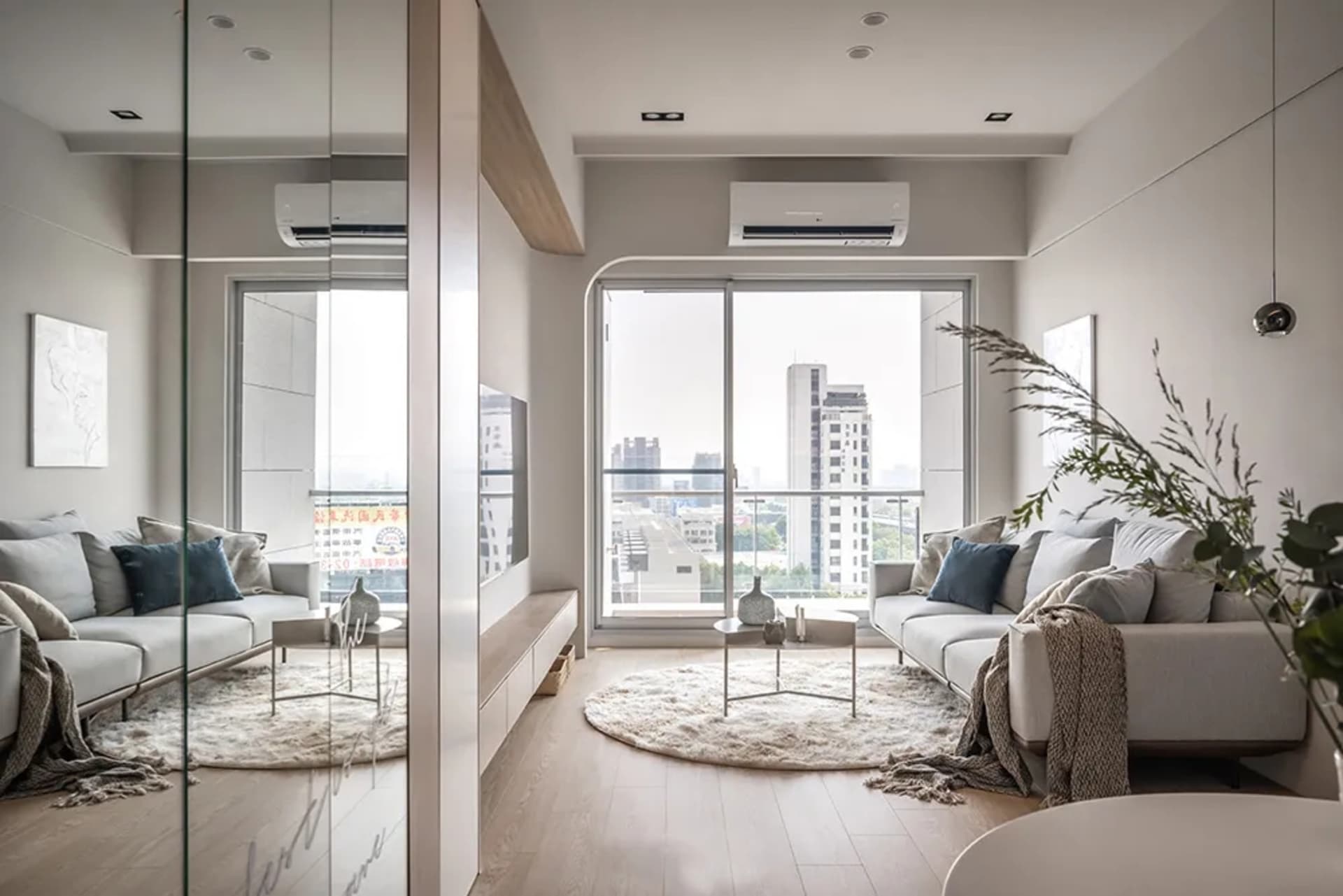 Modern minimalist living room featuring a white sofa, wooden accents, and a large window with city view.