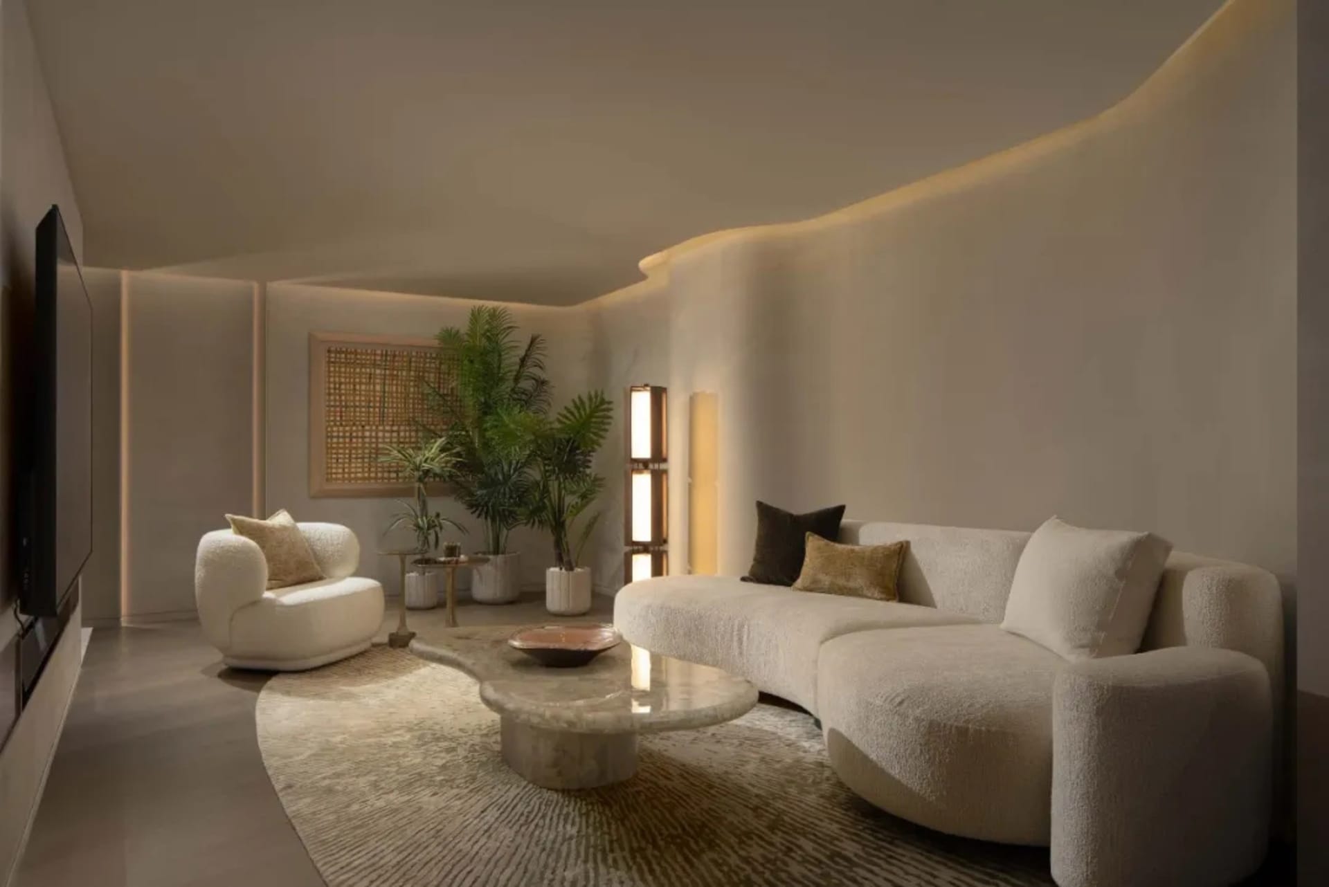 A modern minimalist living room featuring soft furnishings and potted plants.