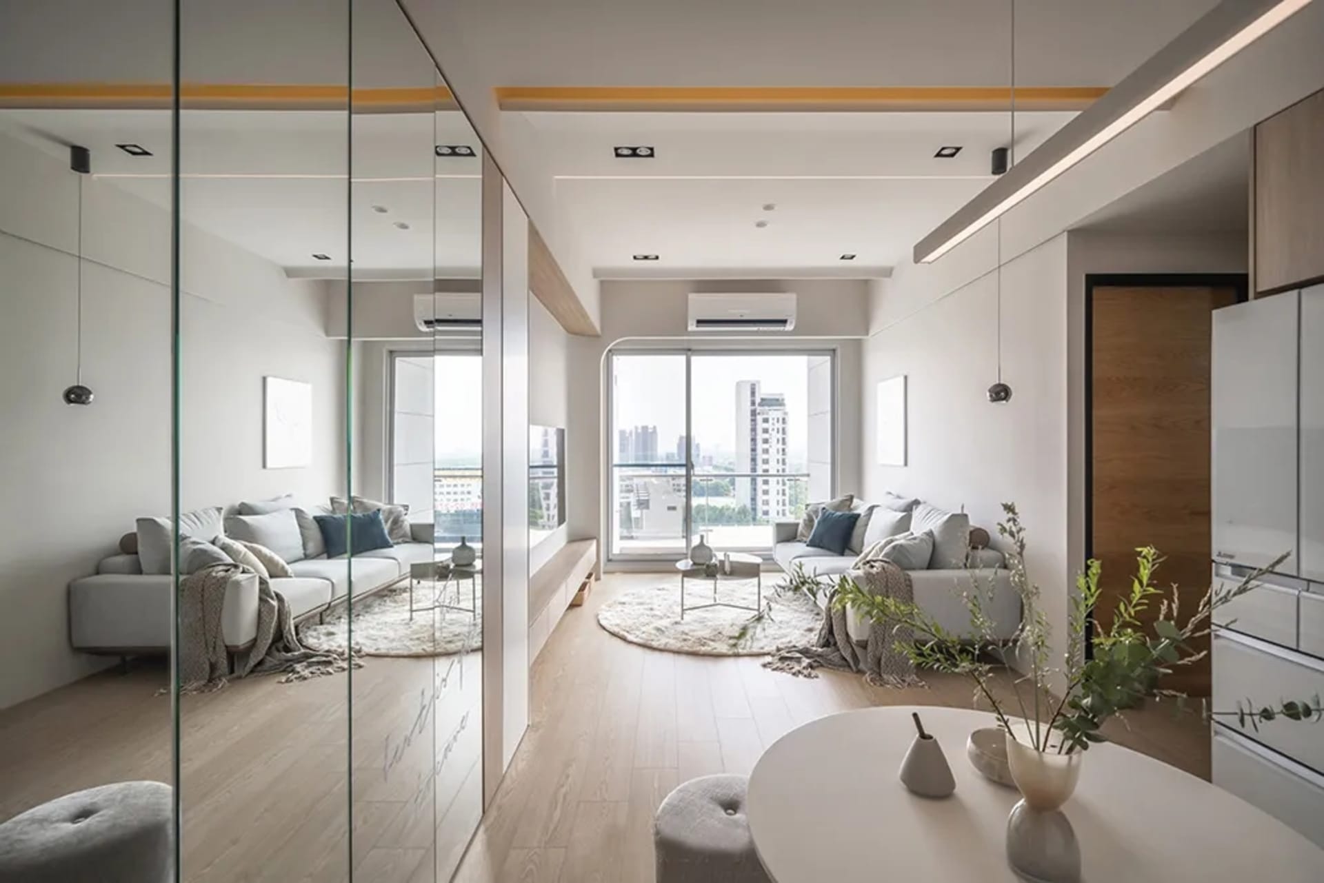 A modern living room featuring comfortable sofas, soft cushions, and minimalistic decor.