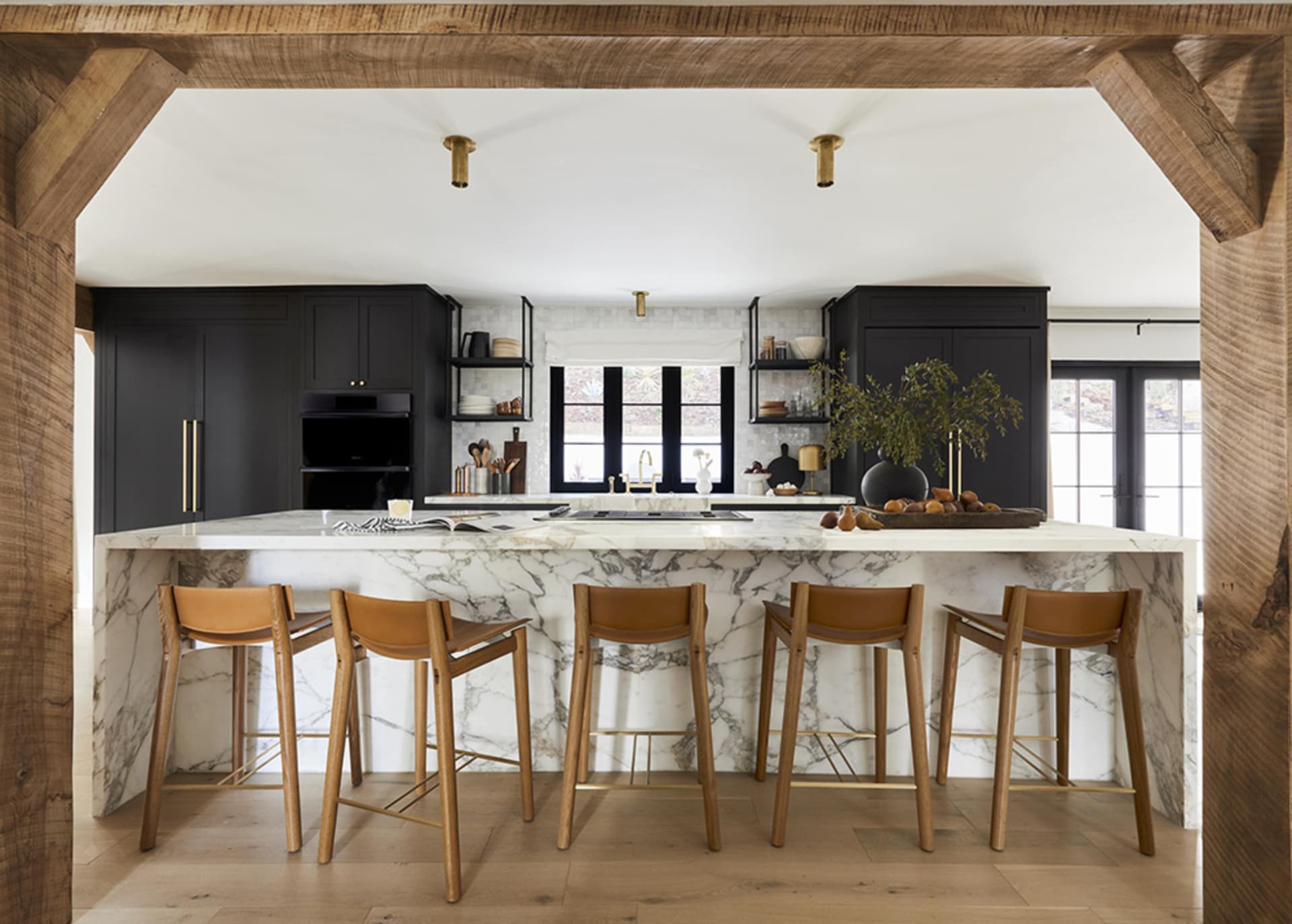 An industrial-style residential kitchen with a marble countertop and wooden chairs.