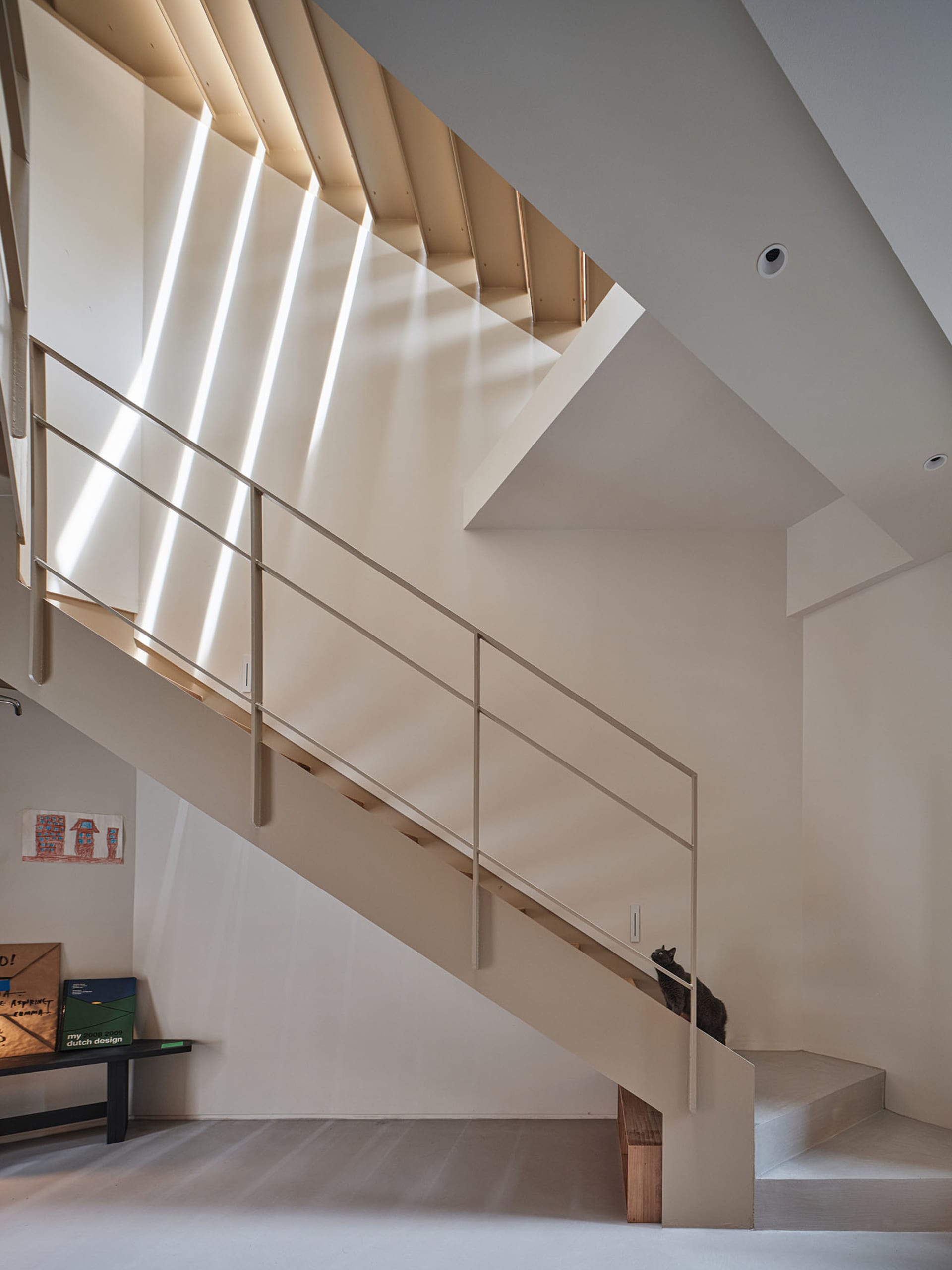 Modern, industrial-style staircase with metallic railing and steps, featuring geometric shapes and a minimalist aesthetic.