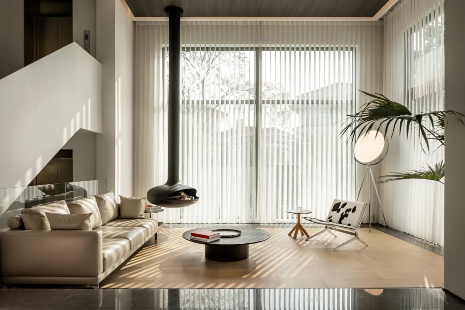 A modern minimalist living room with large glass windows, a sleek sofa, and a central coffee table.
