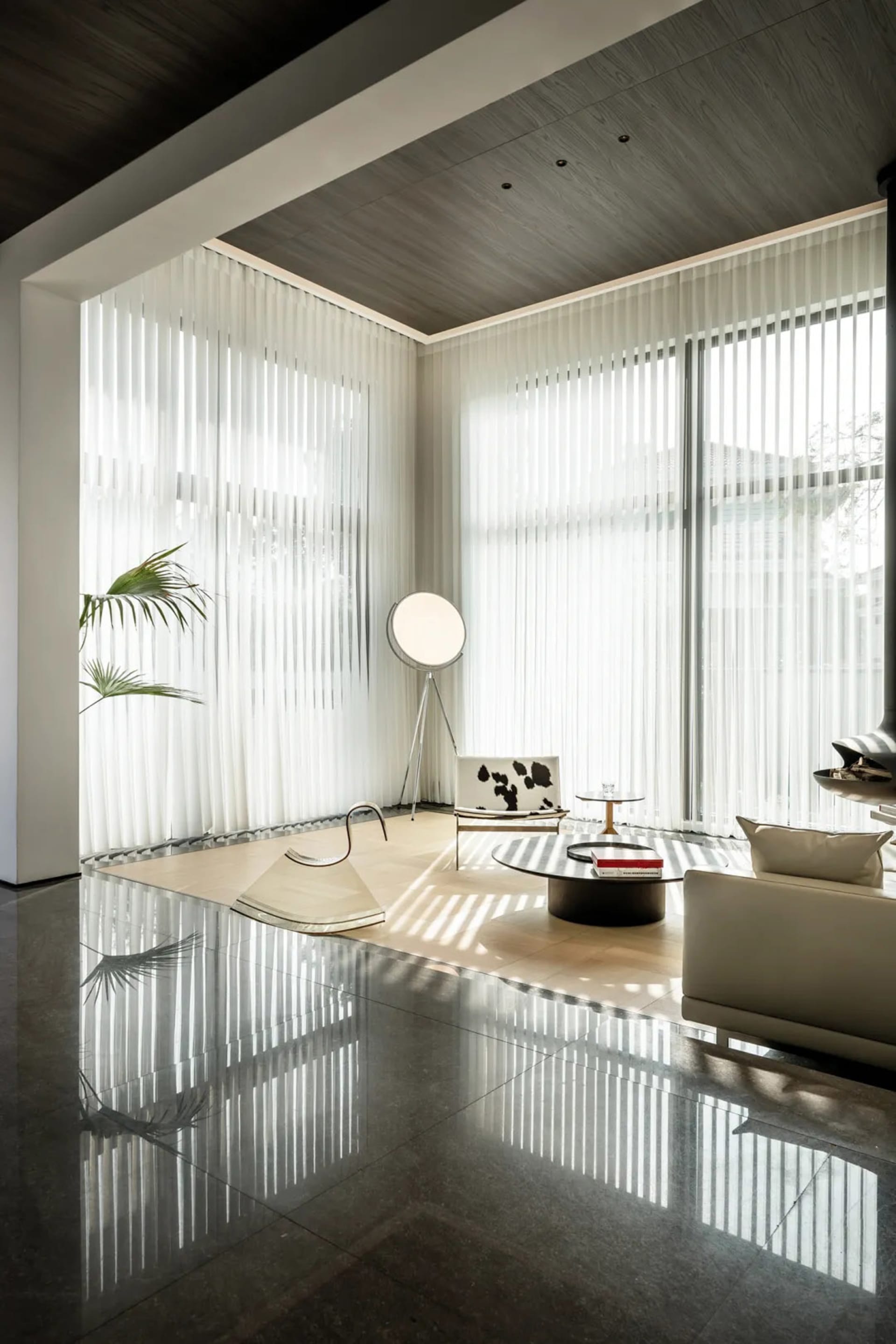 A minimalist living room with transparent curtains and polished concrete flooring.
