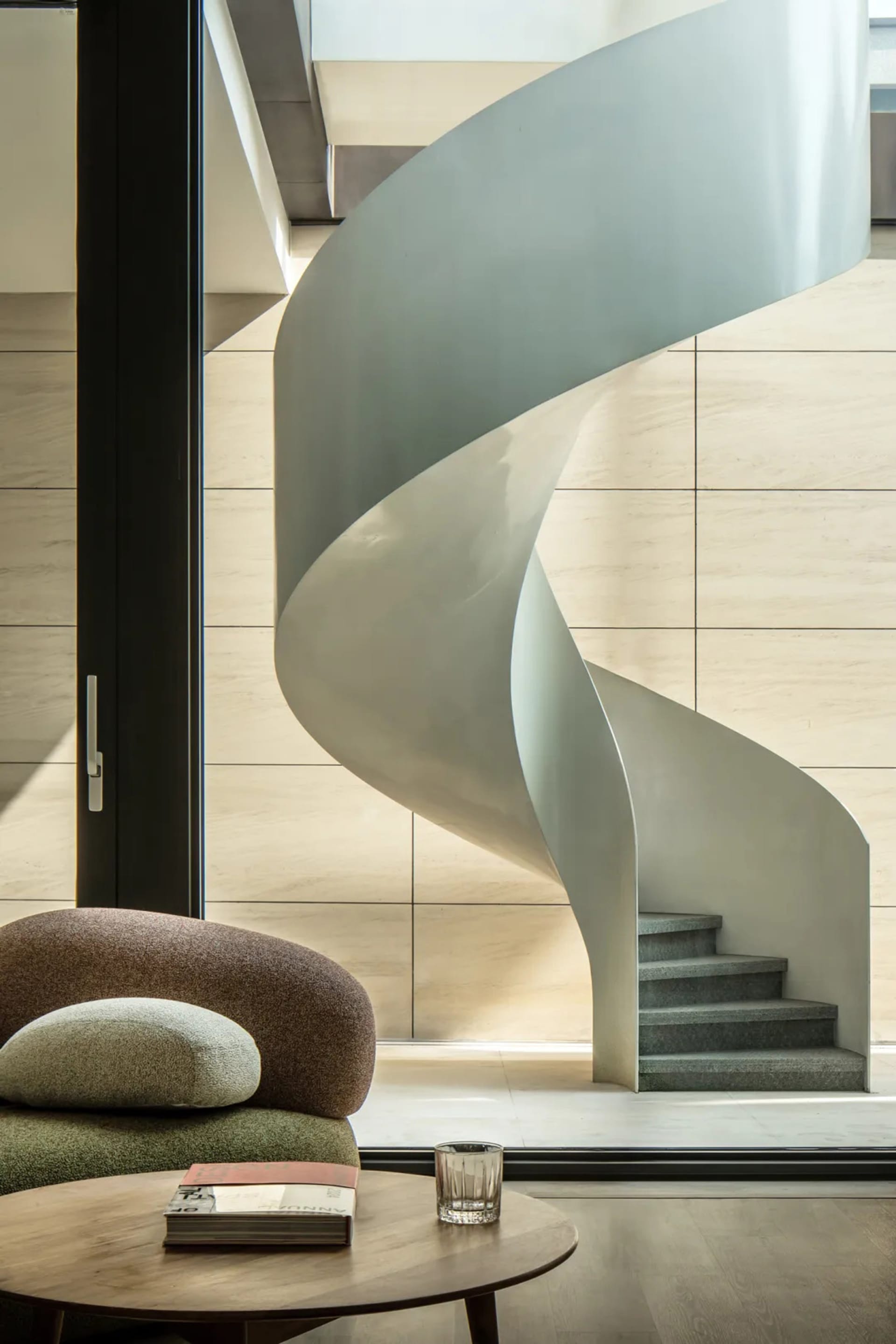 A modern interior design featuring a concrete spiral staircase with minimalist aesthetics.