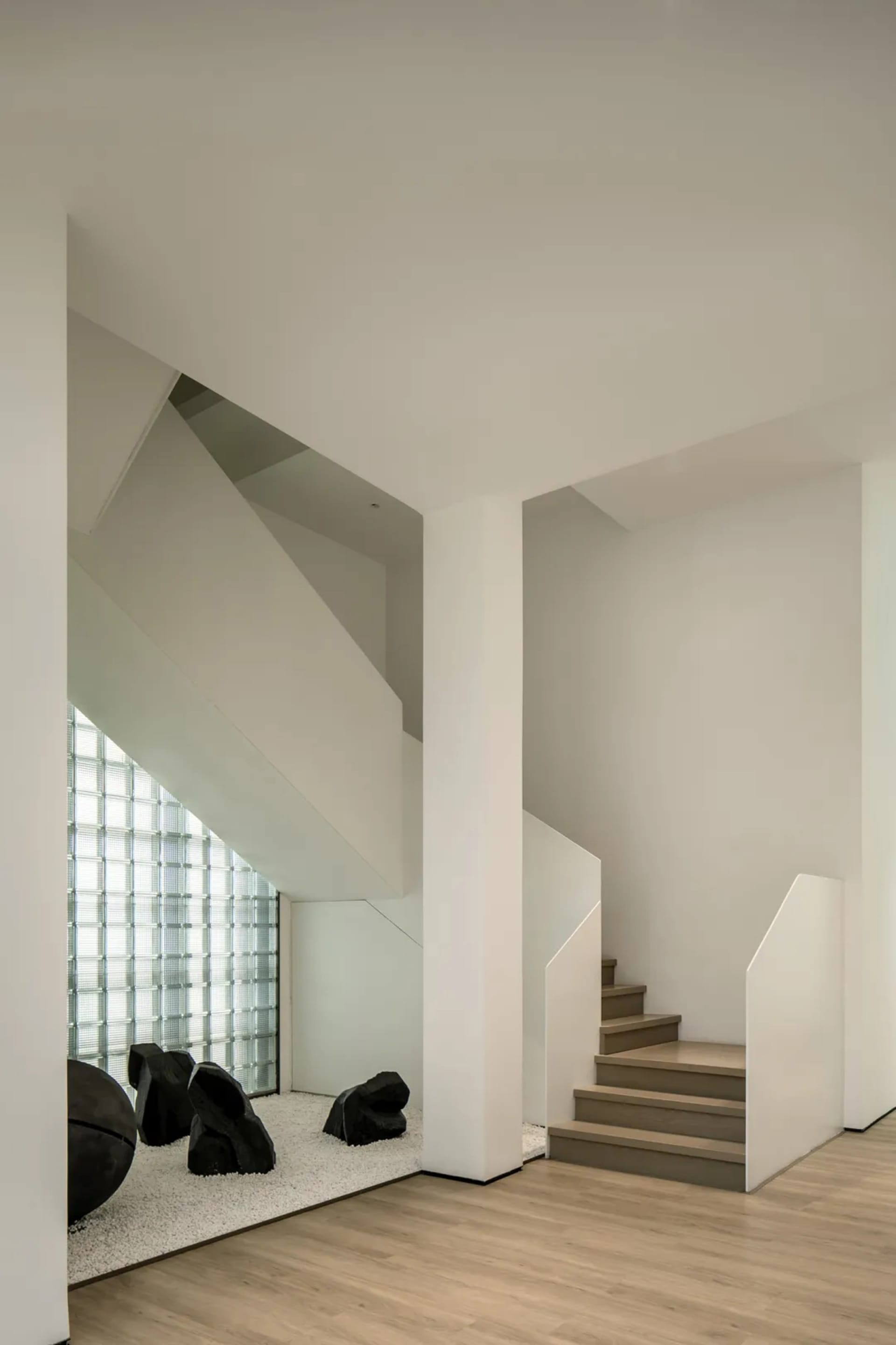 Modern interior space featuring glass walls, concrete elements, wooden stairs, and carpet flooring.