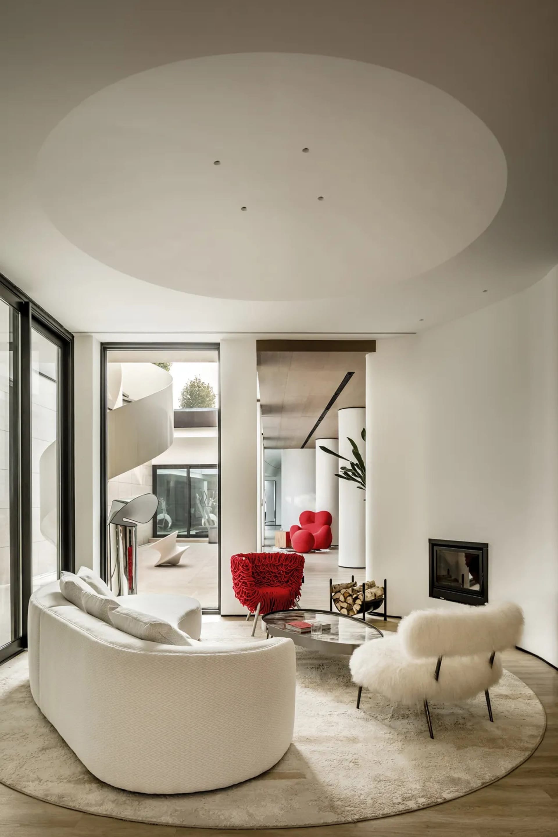 Modern living room with white and red furniture, circular ceiling, and large windows.