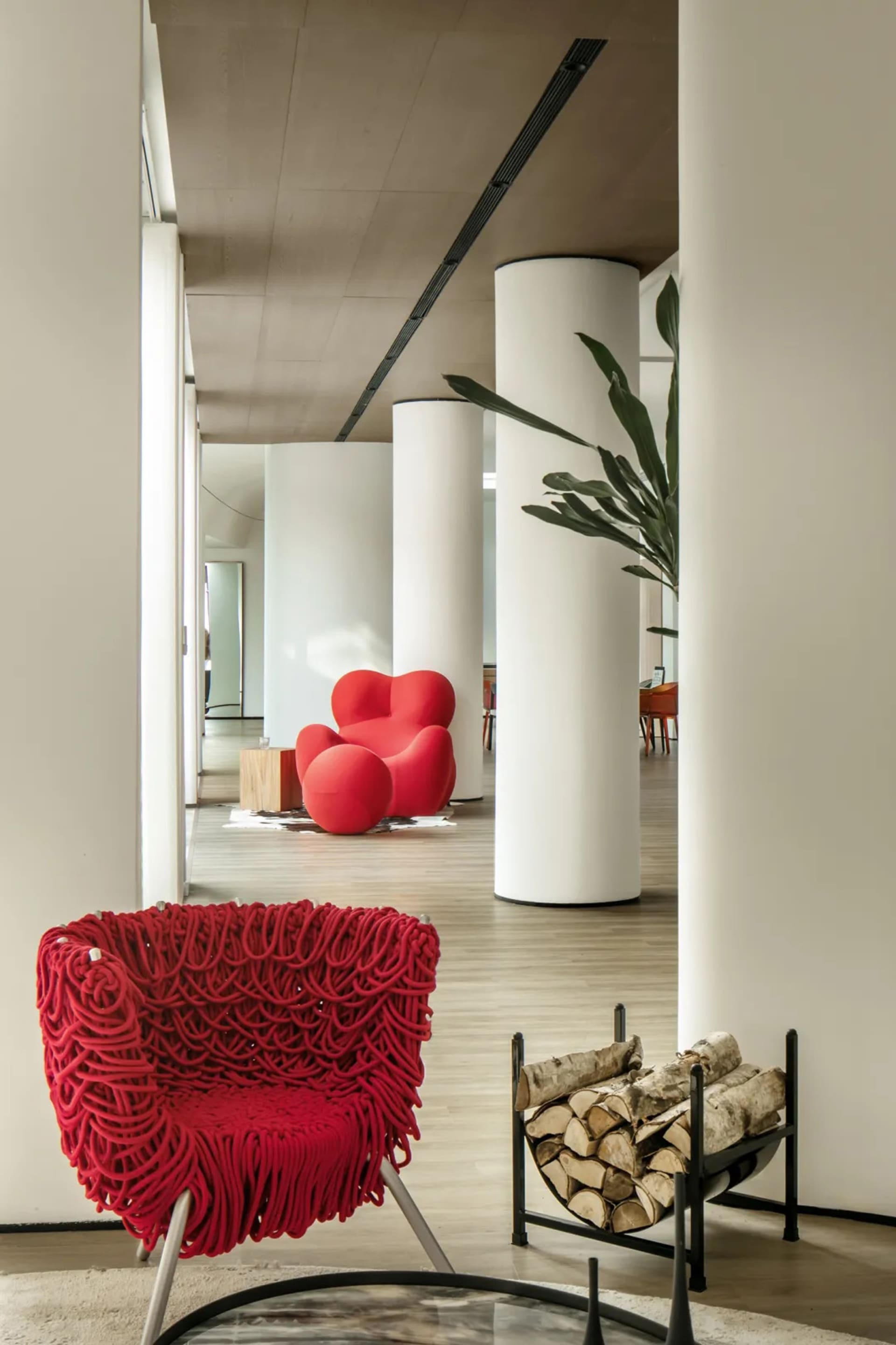 Modern interior design featuring wooden columns and a red knit-fabric covered chair.