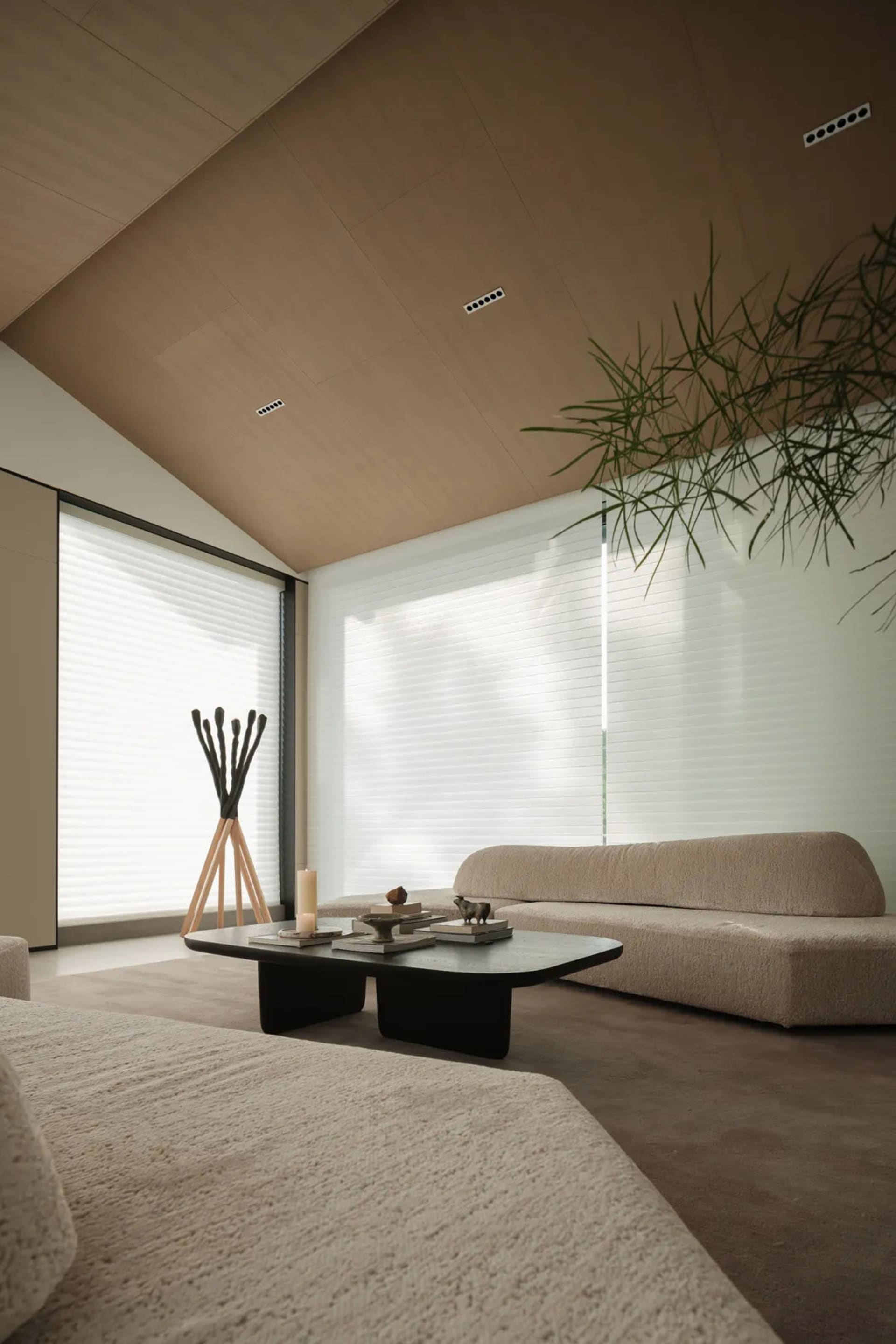 Modern, minimalist living room with textured fabric couches, a low coffee table, and a large window with blinds.