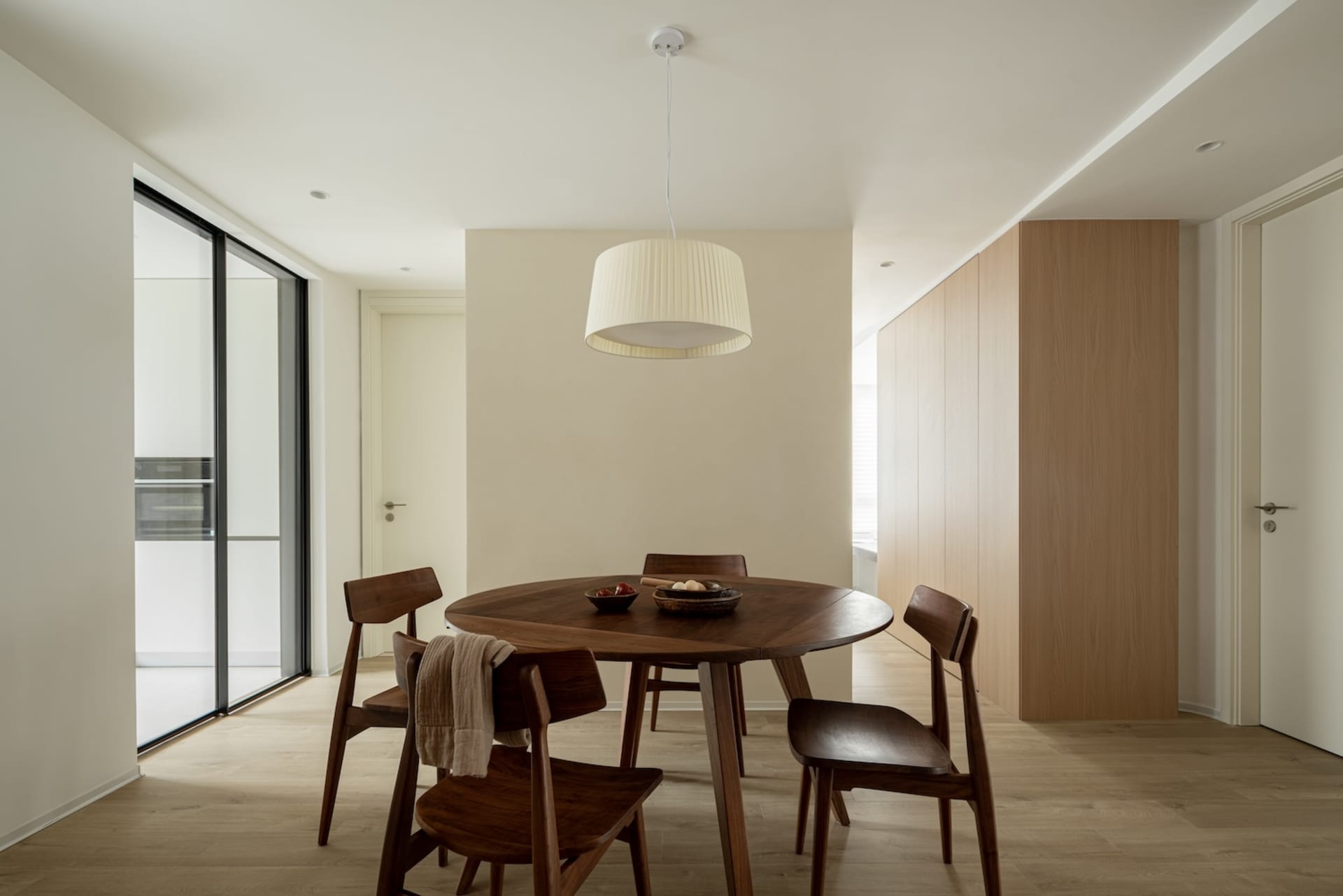A minimalist residential kitchen with a wooden floor, table, and chairs.