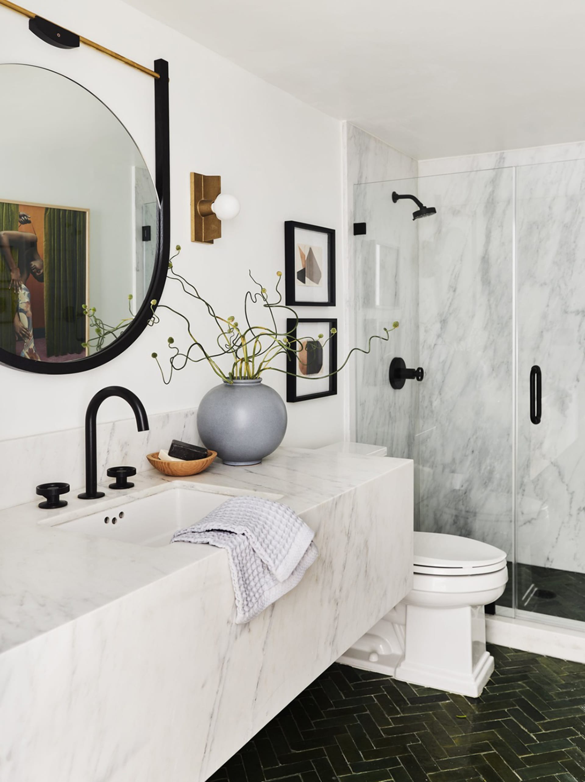 Modern bathroom with marble walls and floor, white sink, and black fixtures.