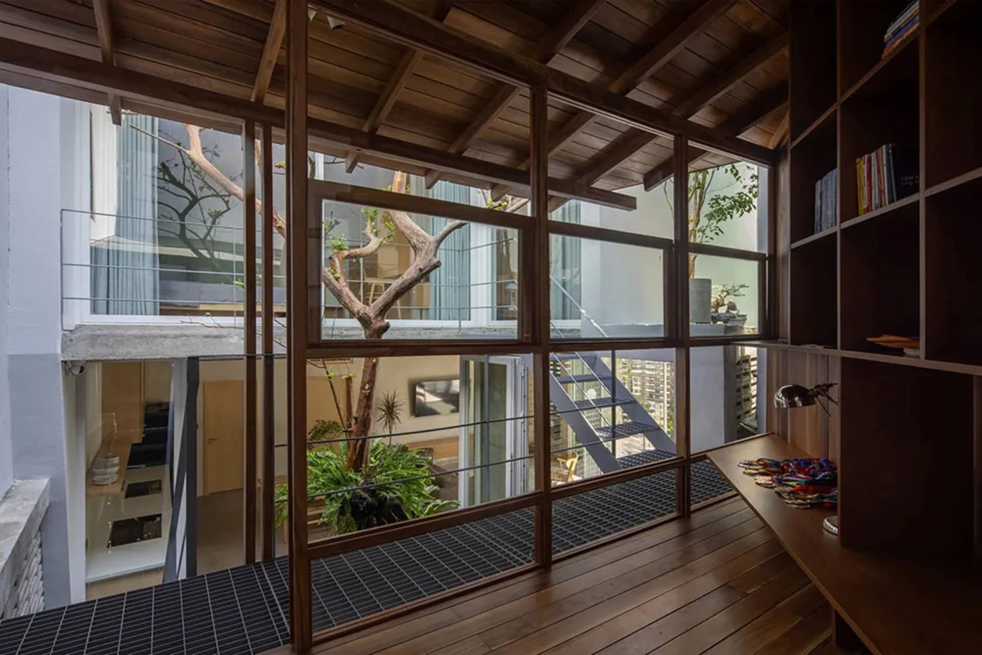 Modern residential interior featuring exposed wooden beams, large windows, and concrete flooring.