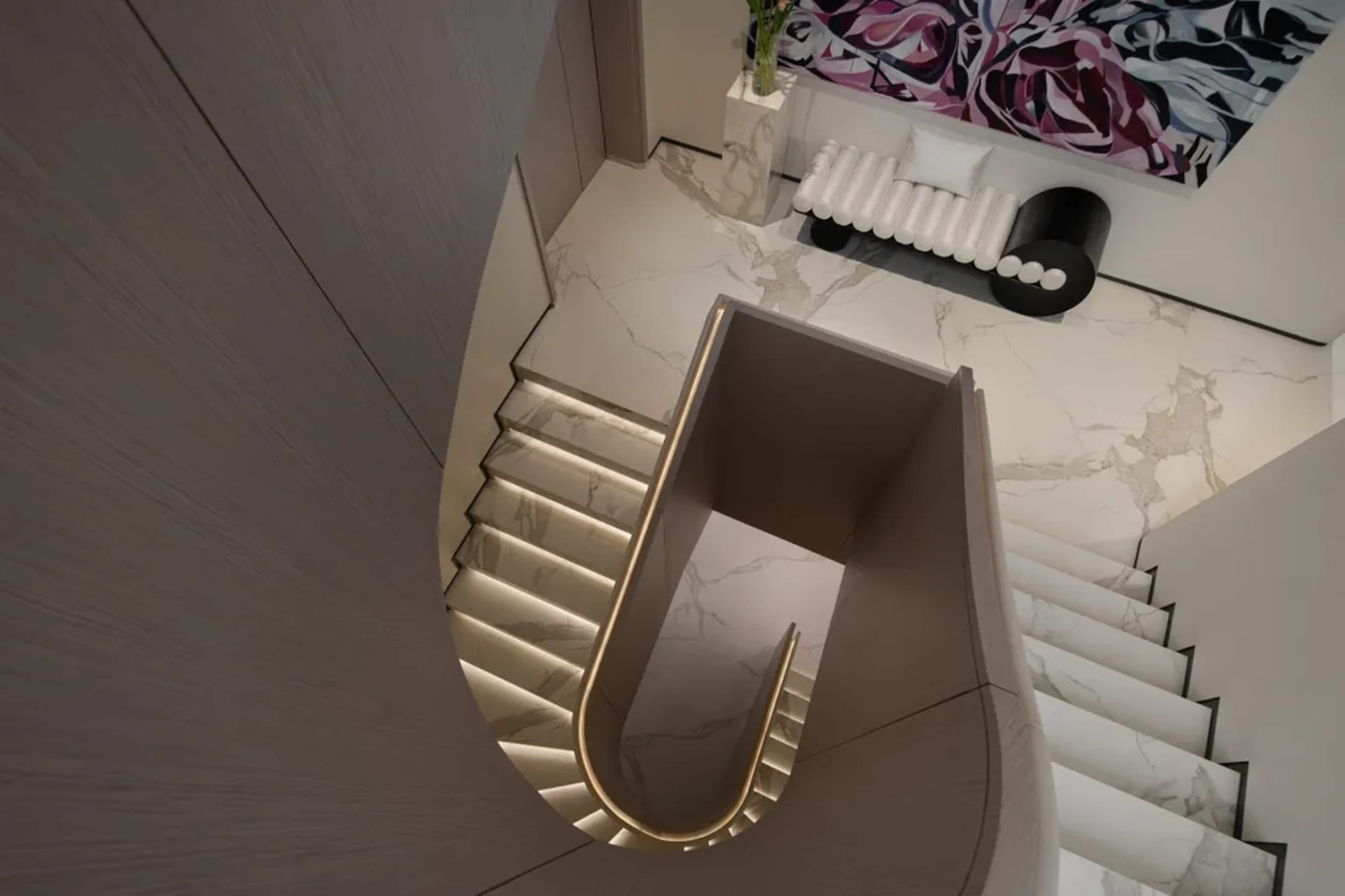 A modern interior staircase with marble steps and a light-colored wall