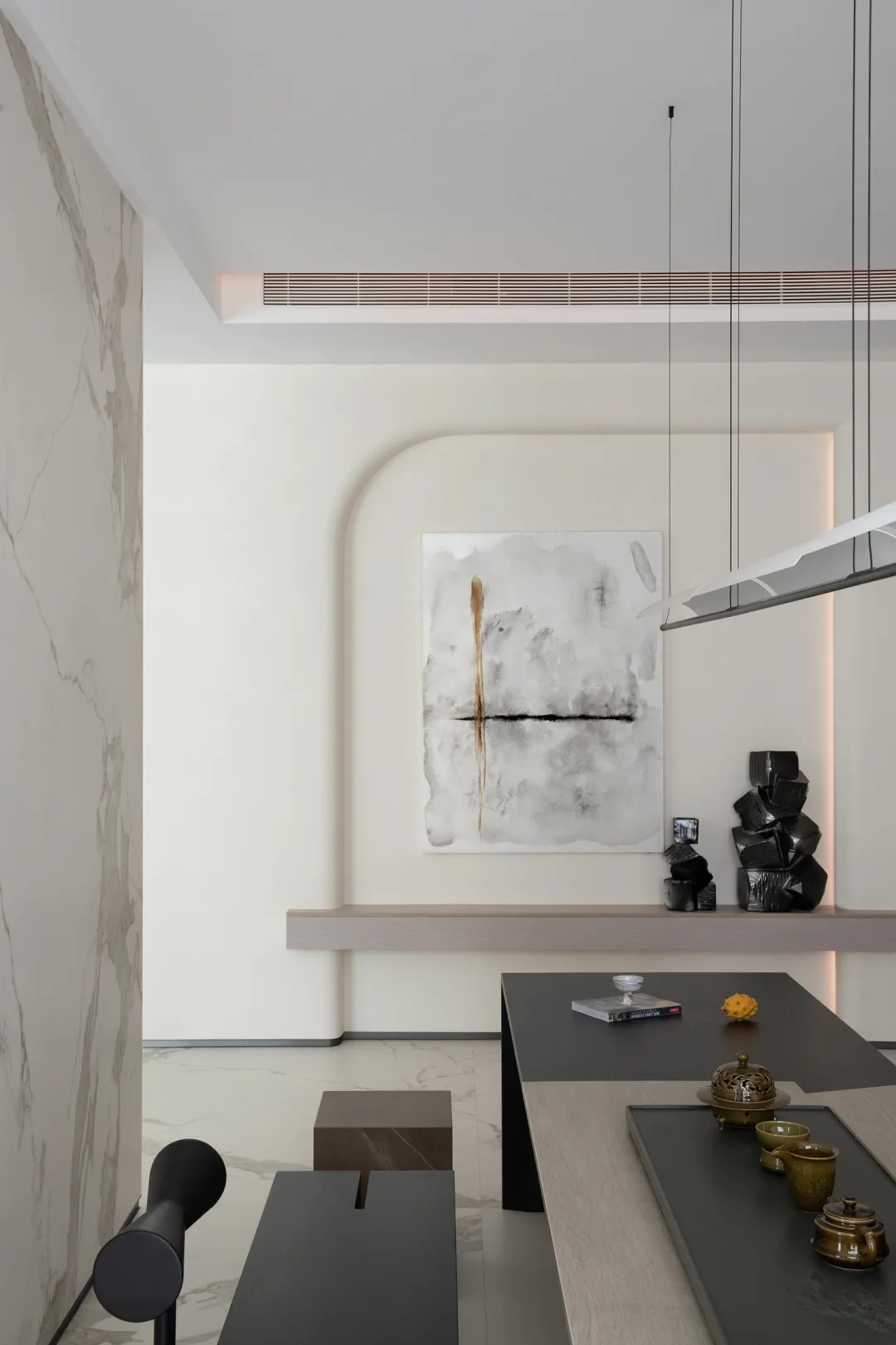 A modern interior design featuring a marble and concrete wall in a living and dining room setting.