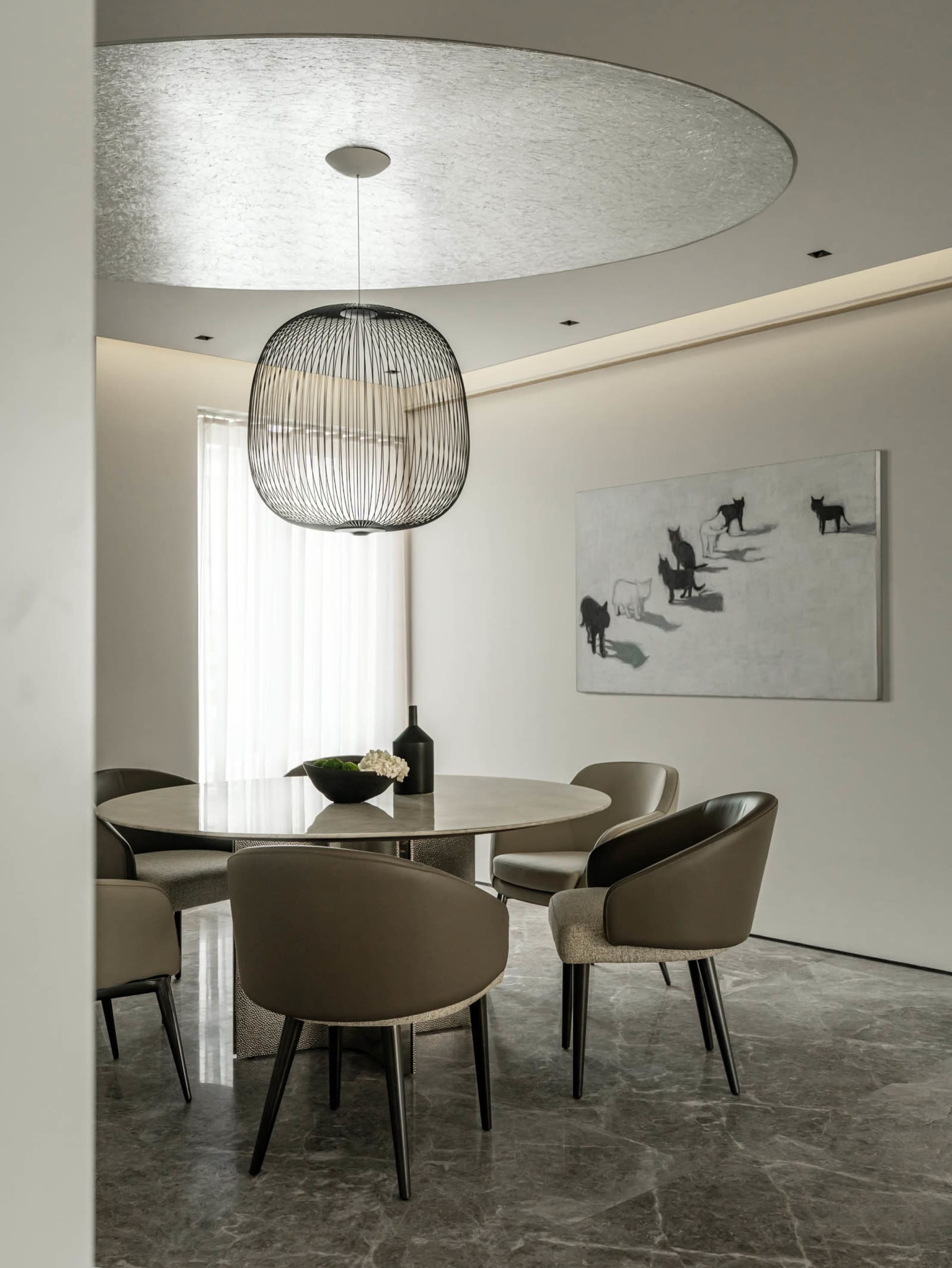 A modern minimalist dining room with a round marble table, upholstered leather chairs, and a black wireframe pendant light ha