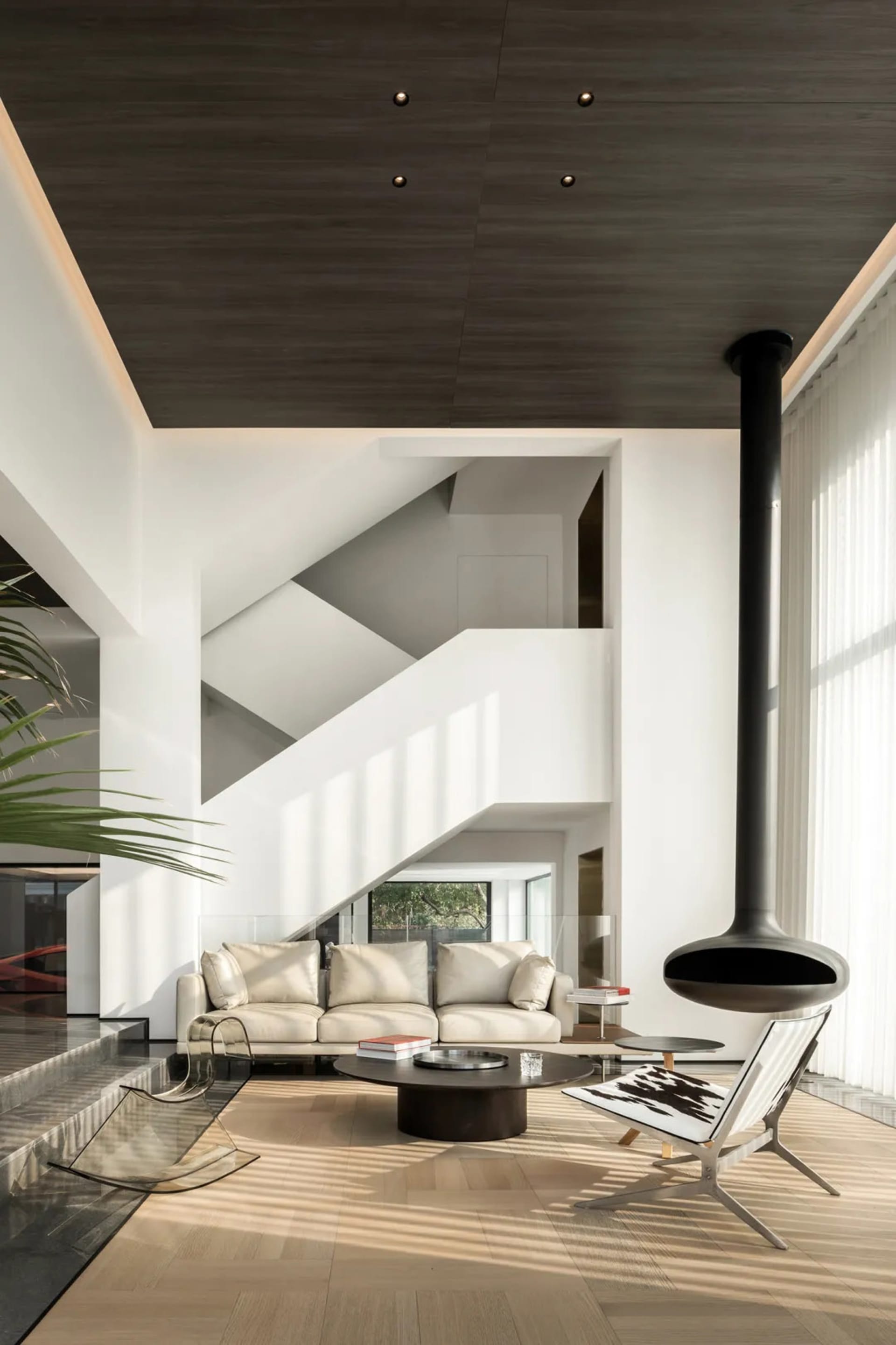 A minimalist living room with a white sofa, glass coffee table, and wooden floor.