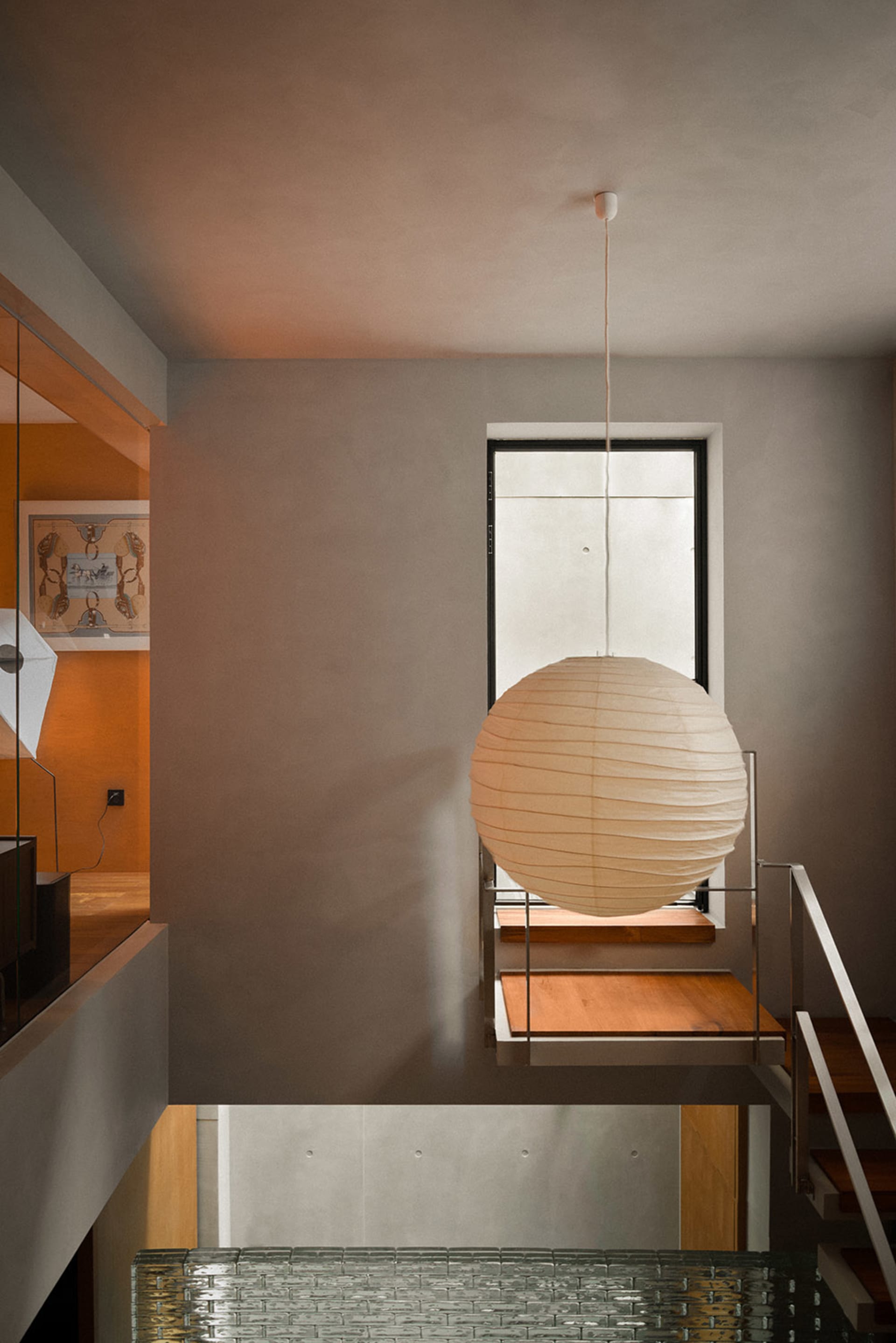 A minimalist interior with wooden elements and a spherical lamp hanging from the ceiling.
