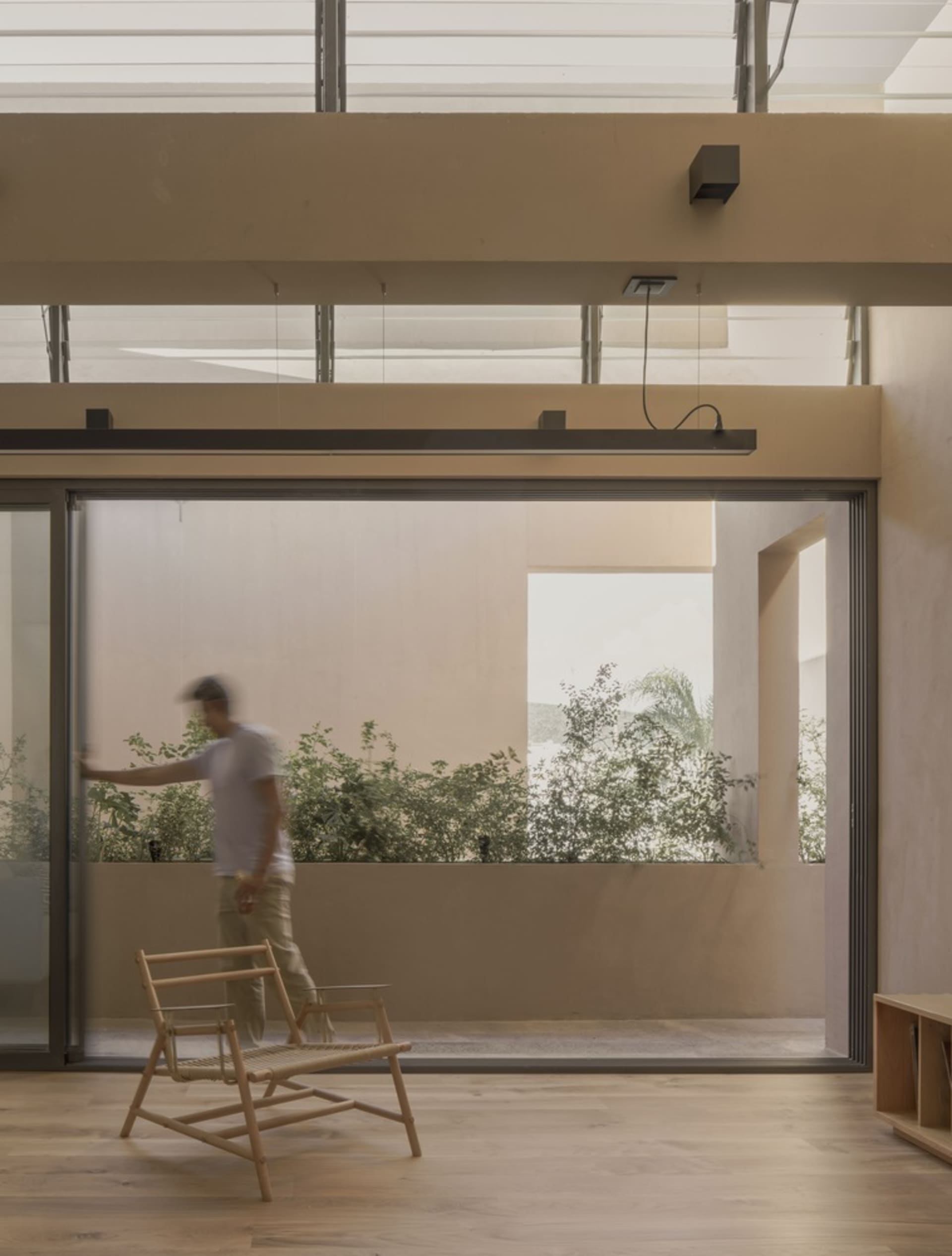 A modern residential room with wooden flooring and a large glass window.