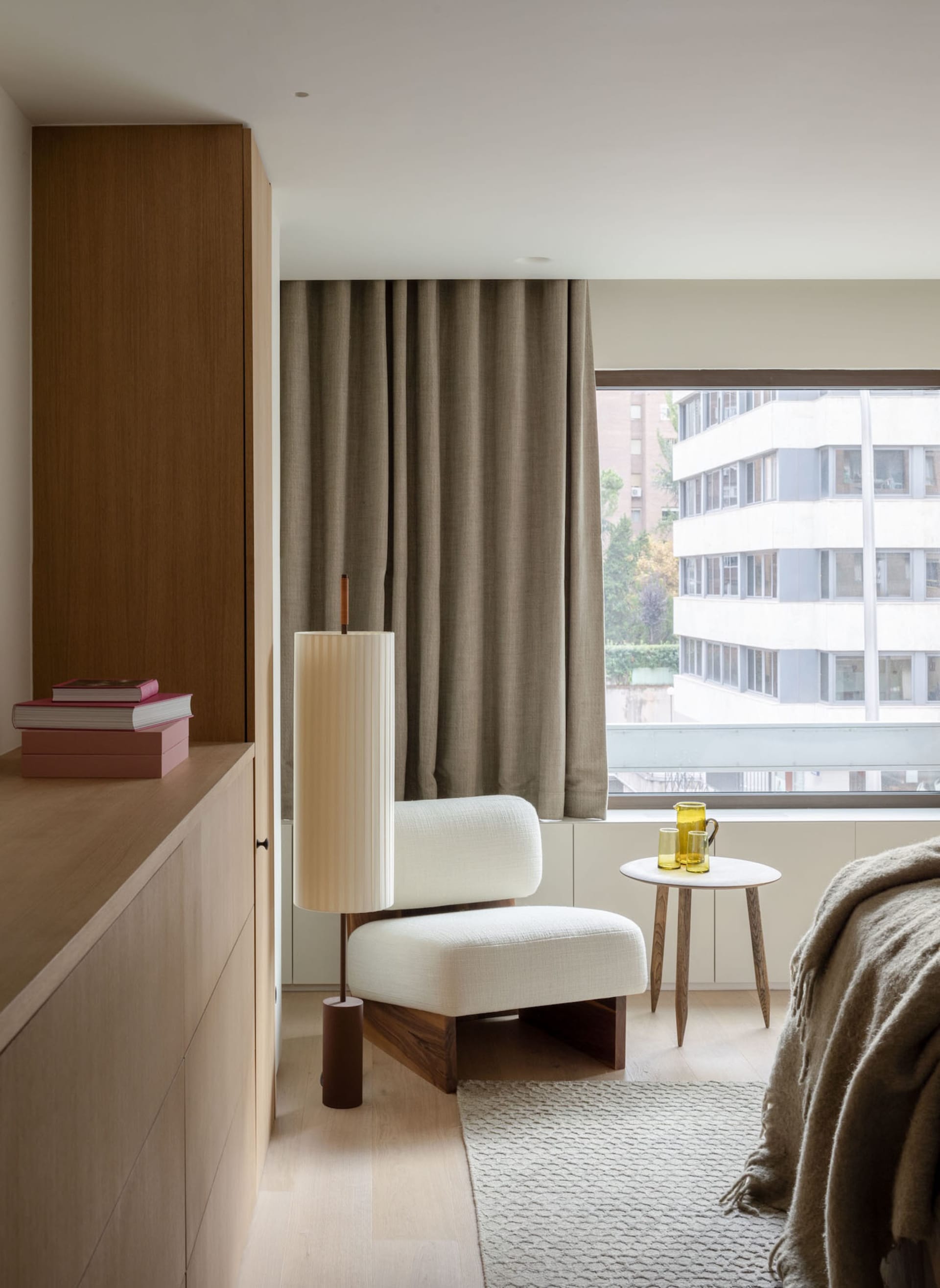 Modern minimalist bedroom featuring sleek white furniture, wooden accents, and floor-to-ceiling windows draped with sheer fab