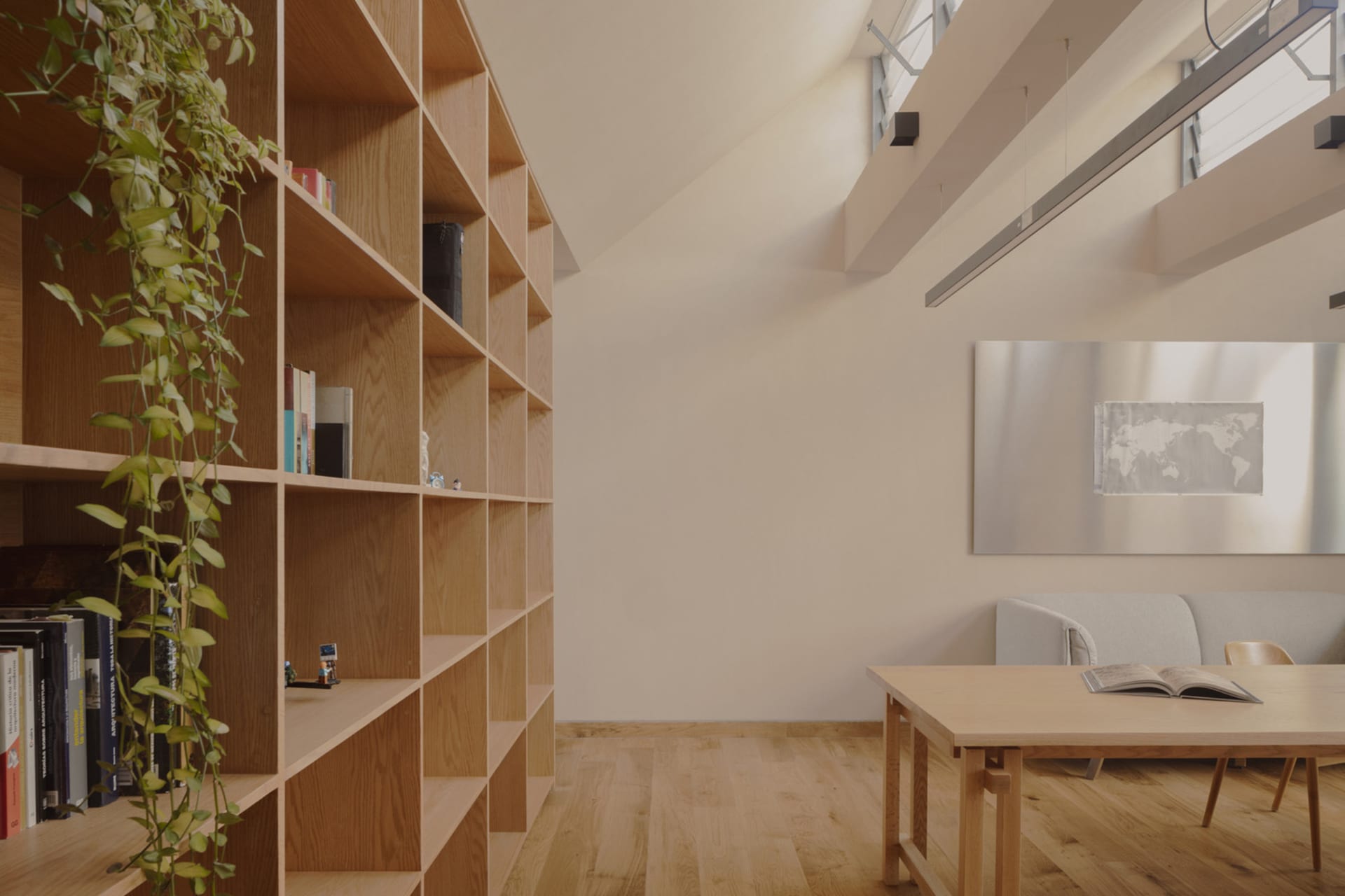 Minimalist living room with wooden shelves, a table, and a world map on the wall.