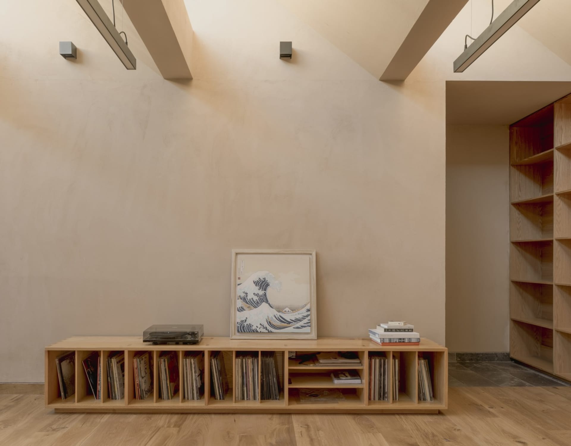 A minimalist living room featuring wooden shelves and a wooden floor.