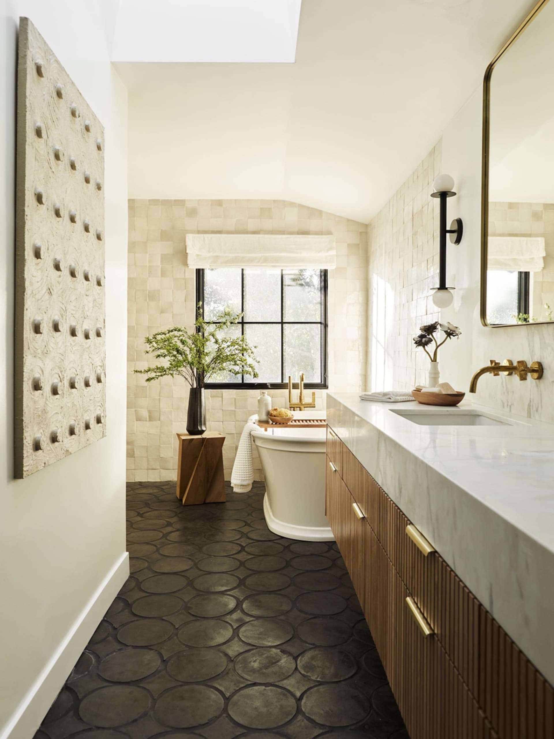 A modern bathroom featuring a tile floor, freestanding bathtub, and marble countertop.