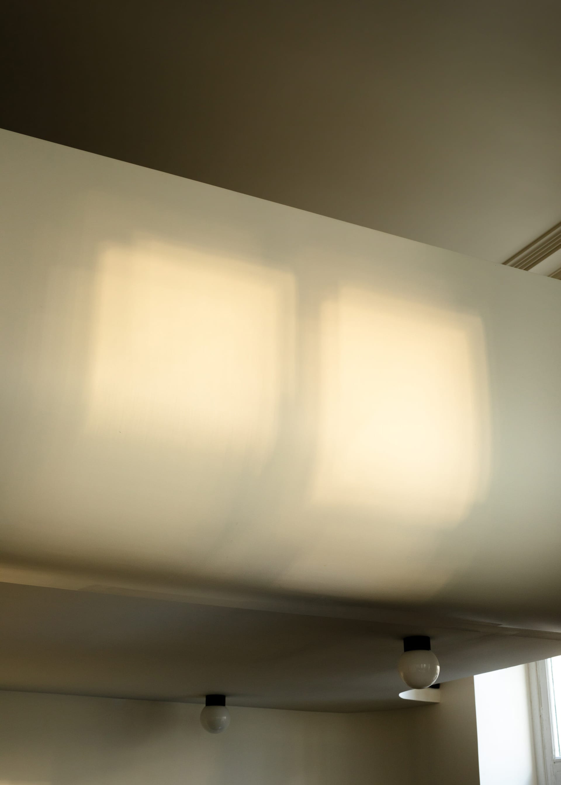 A modern interior space featuring light fixtures casting illuminated squares on the wall.