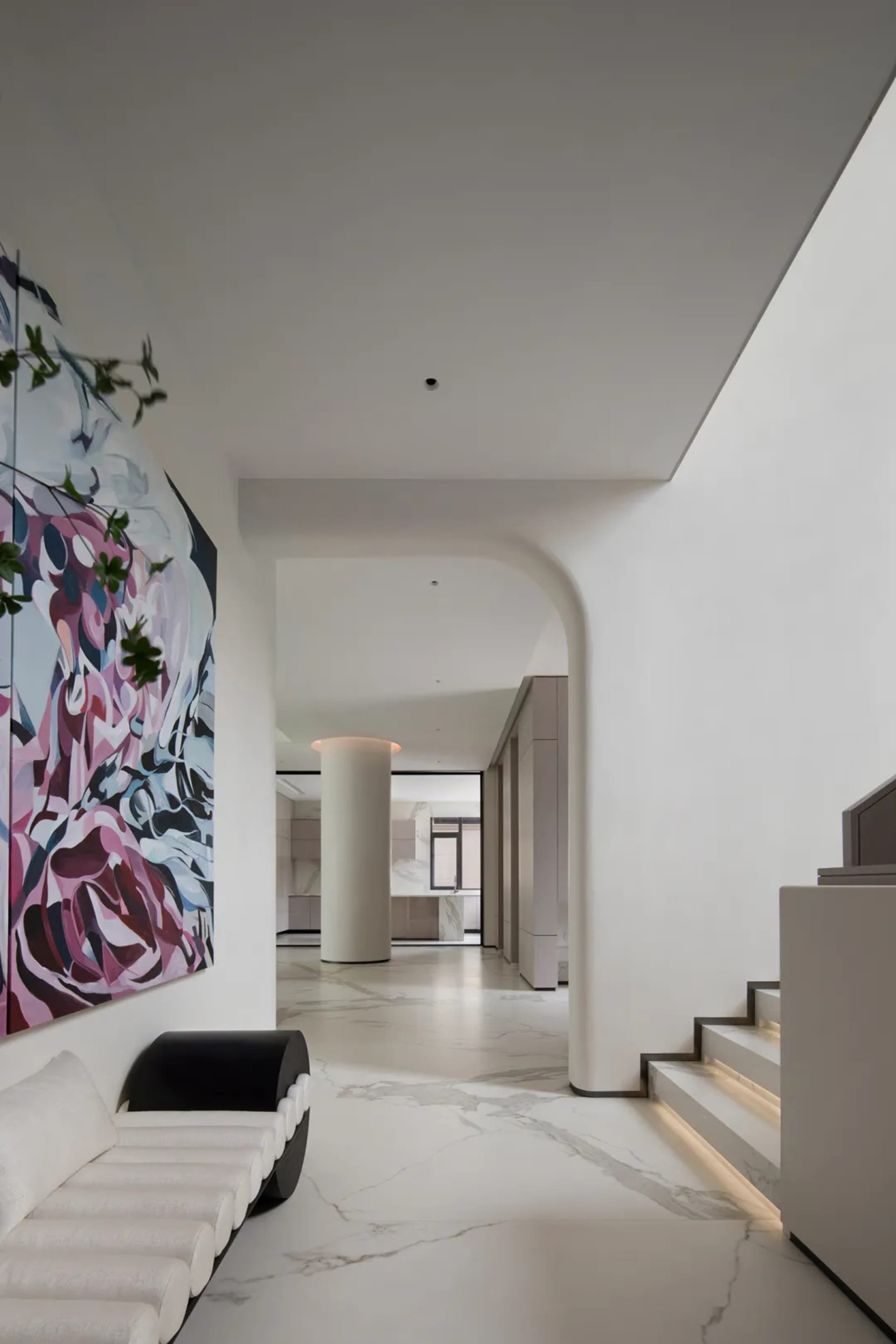 A modern living room featuring marble flooring and a large abstract painting on the wall.
