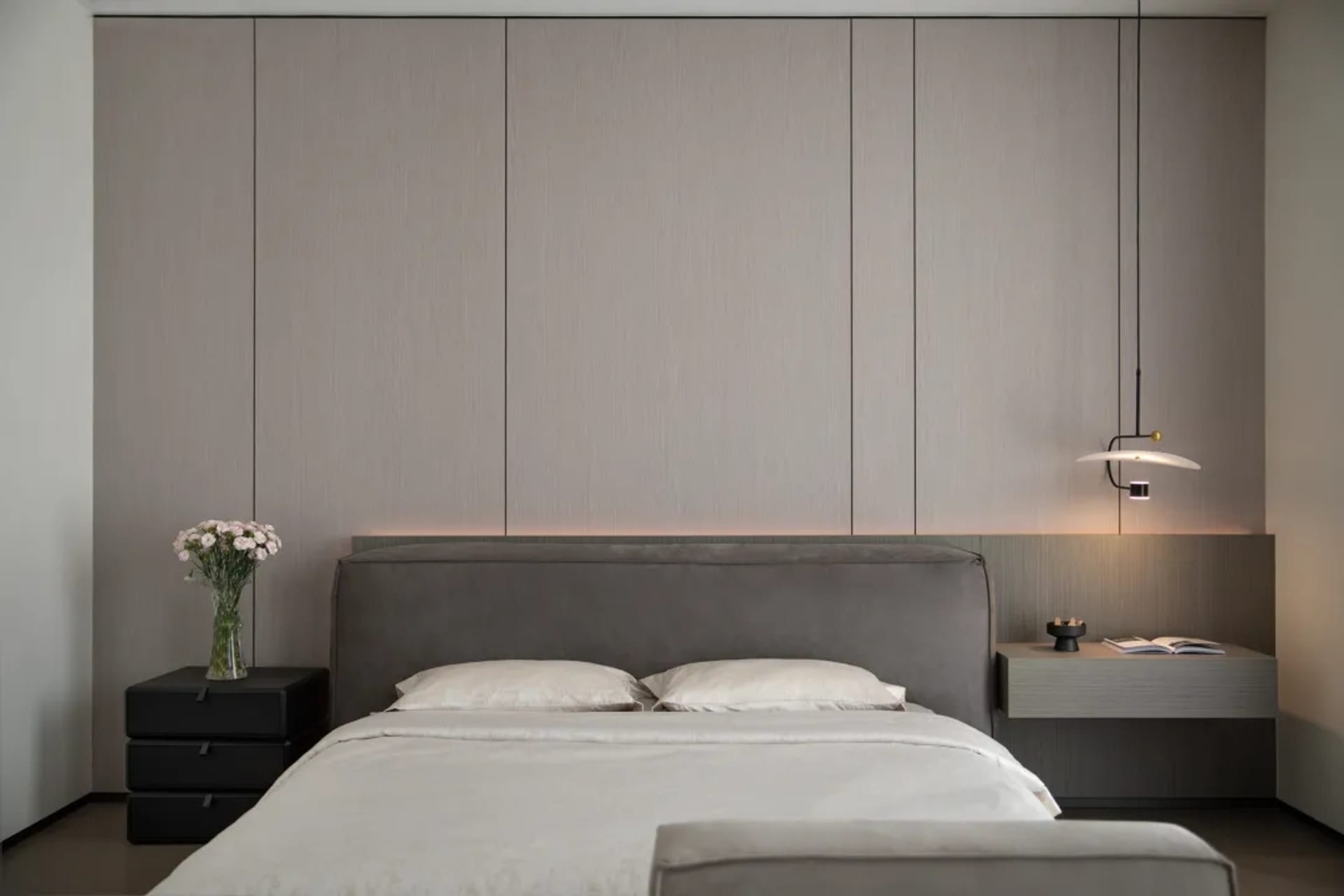 A modern bedroom with a grey upholstered bed and minimalist design elements.