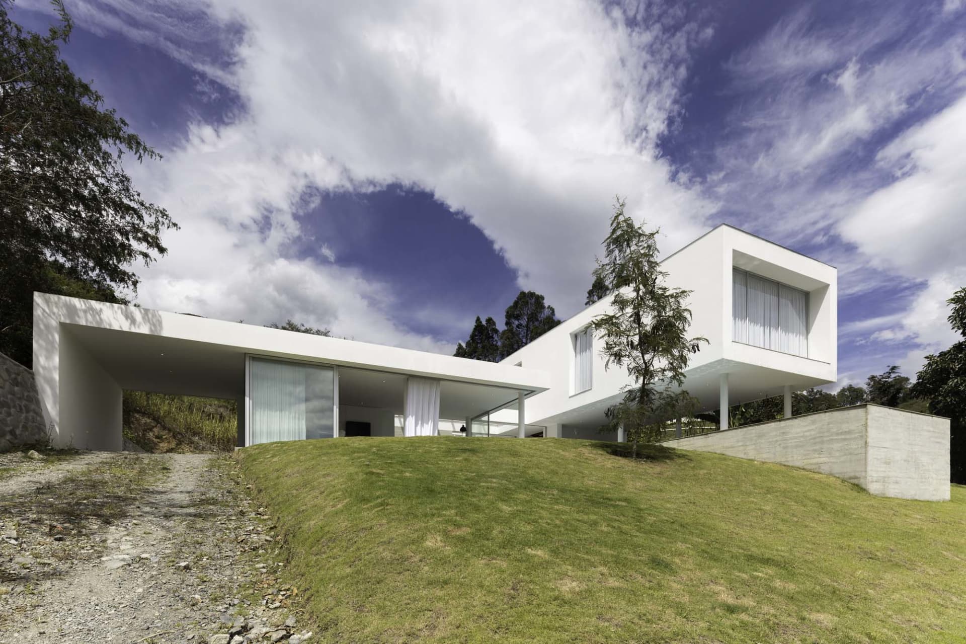 A modern white concrete home with large glass windows and a minimalist design.