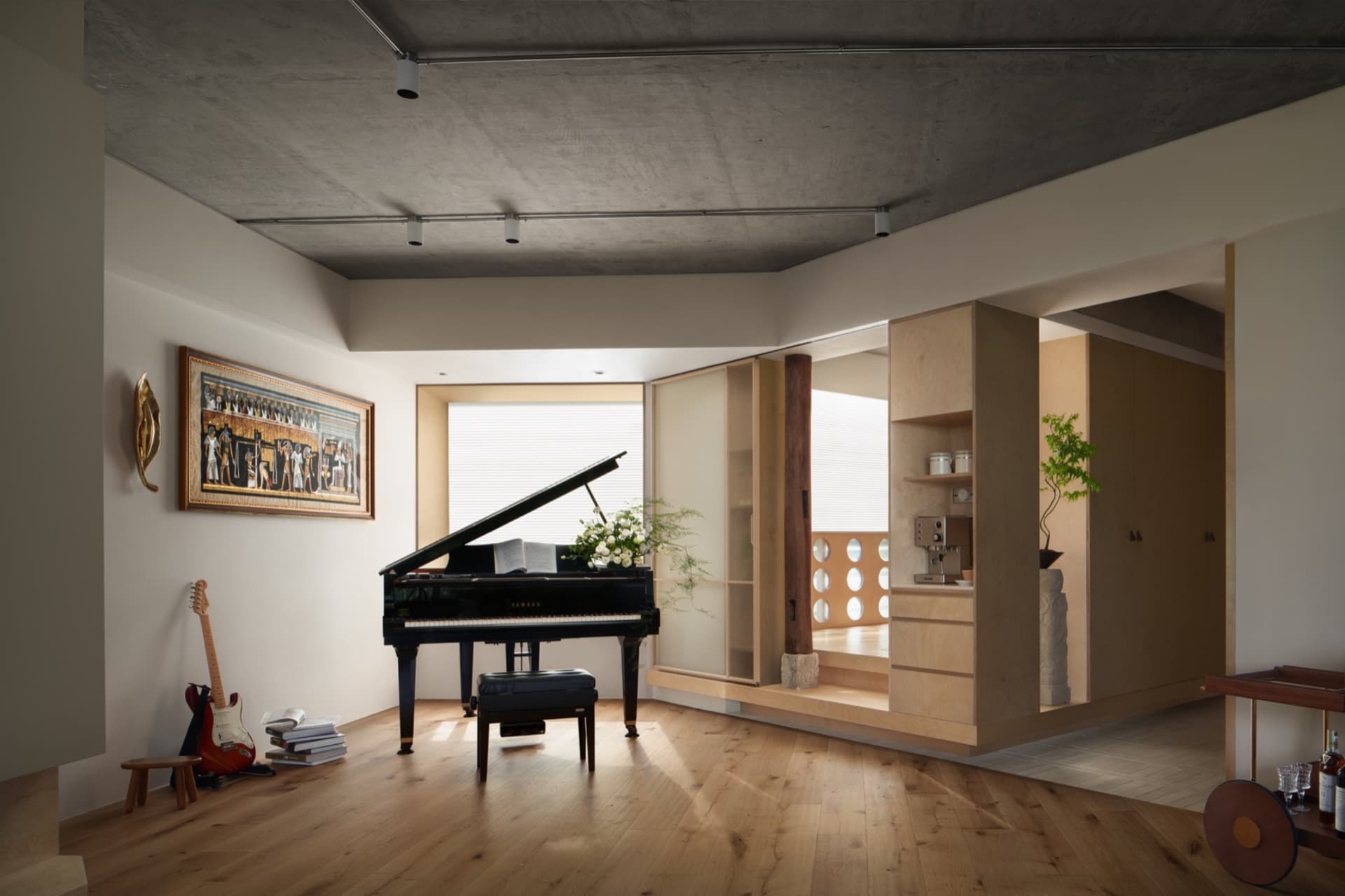 A modern living room featuring a grand piano with flowers and a guitar in the corner.