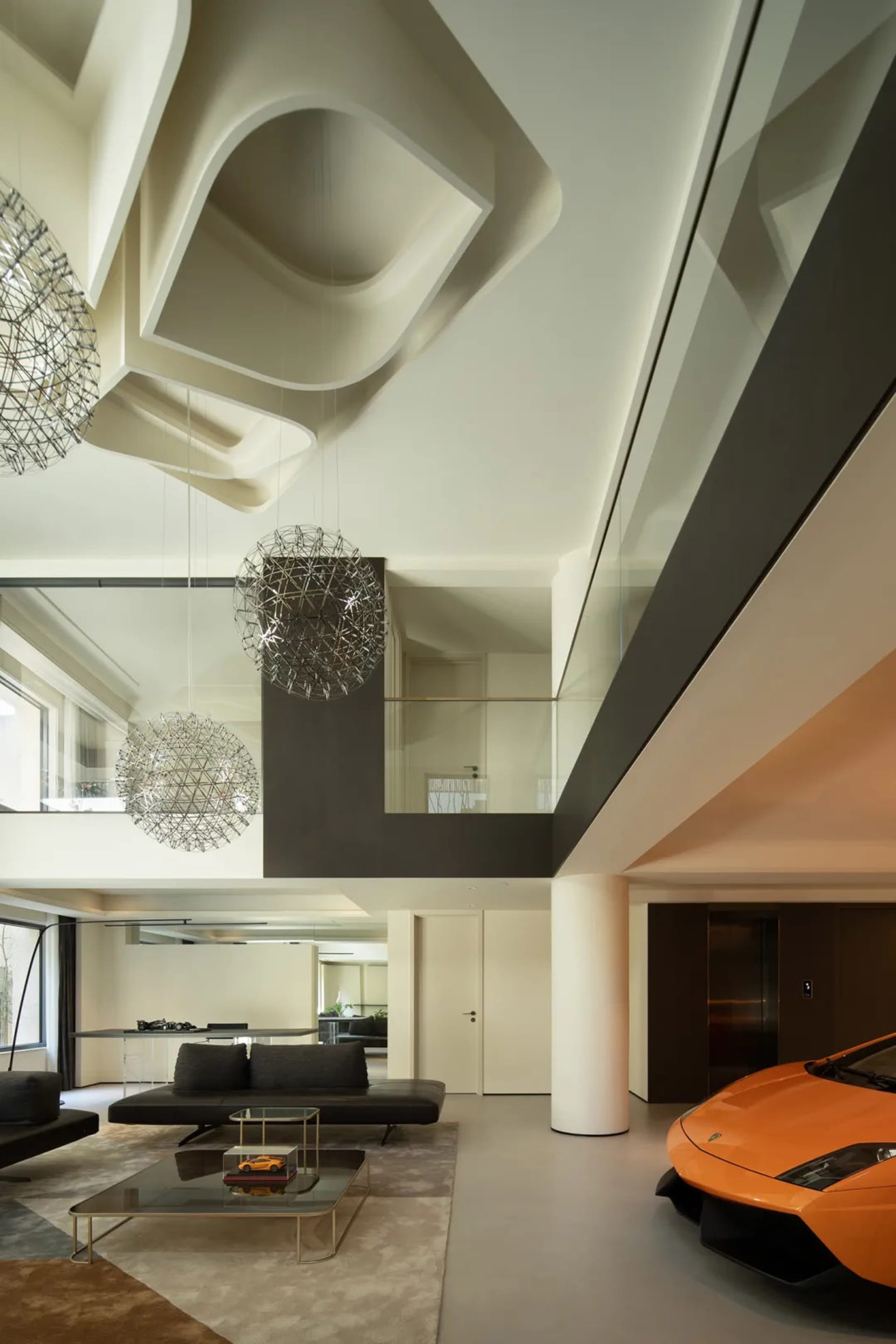 A modern living room featuring a sleek, orange sports car parked indoors, with geometric lighting fixtures and smooth, minima