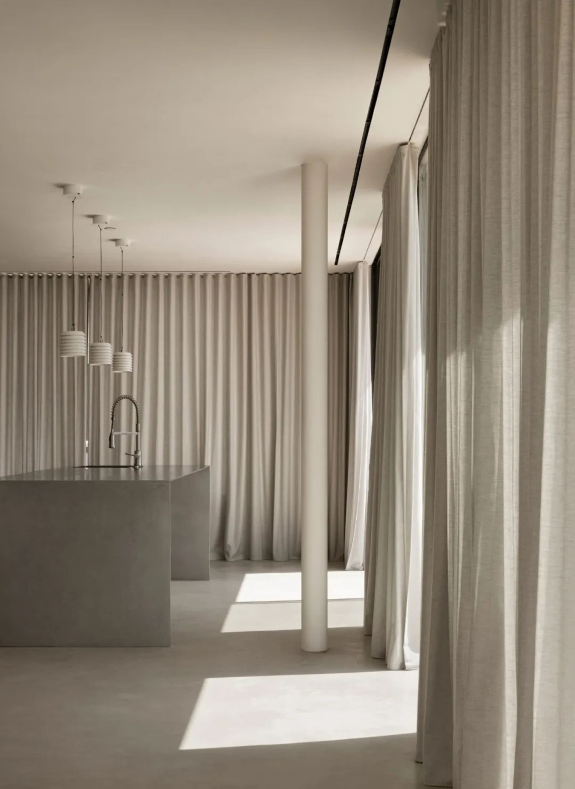 Modern minimalist kitchen with concrete elements and white curtains.