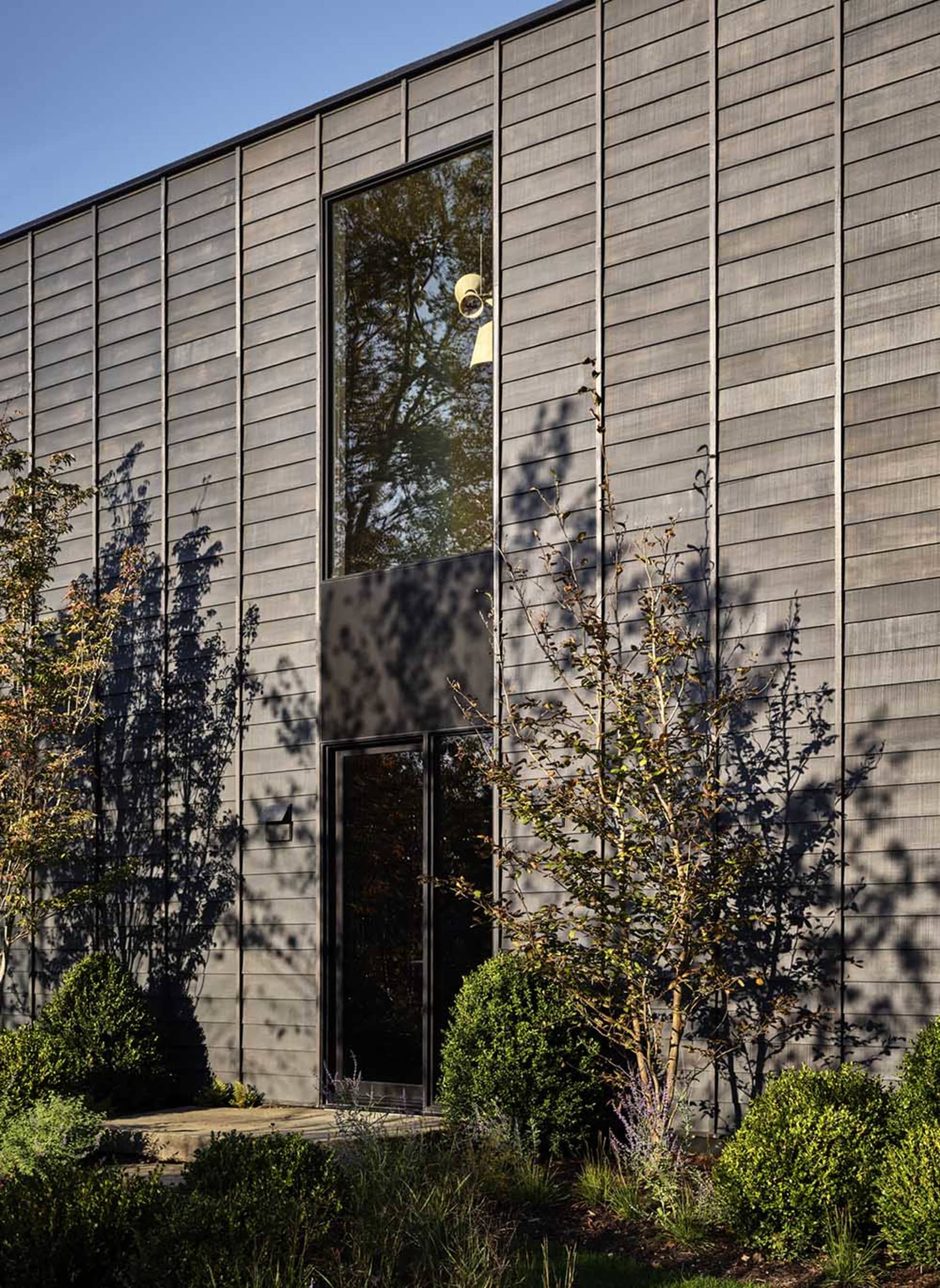 Modern residential building with large vertical windows and metal exterior siding.