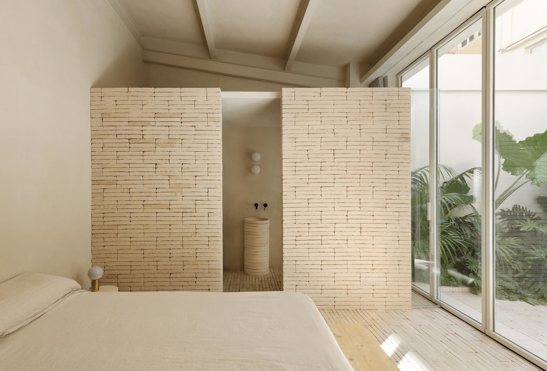 Modern minimalist bedroom with brick walls and natural light.