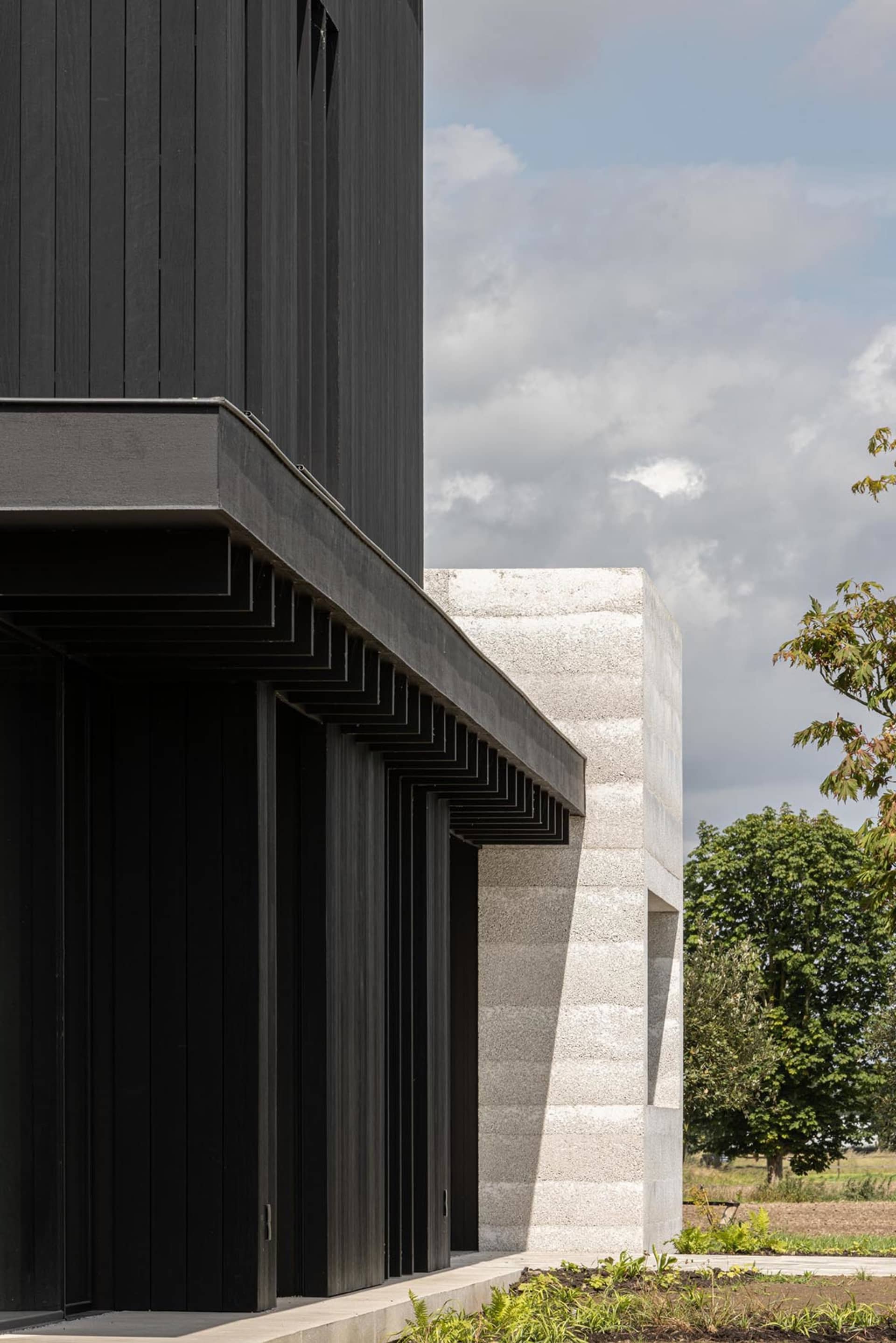 A modern building with black wooden panels and a concrete base.
