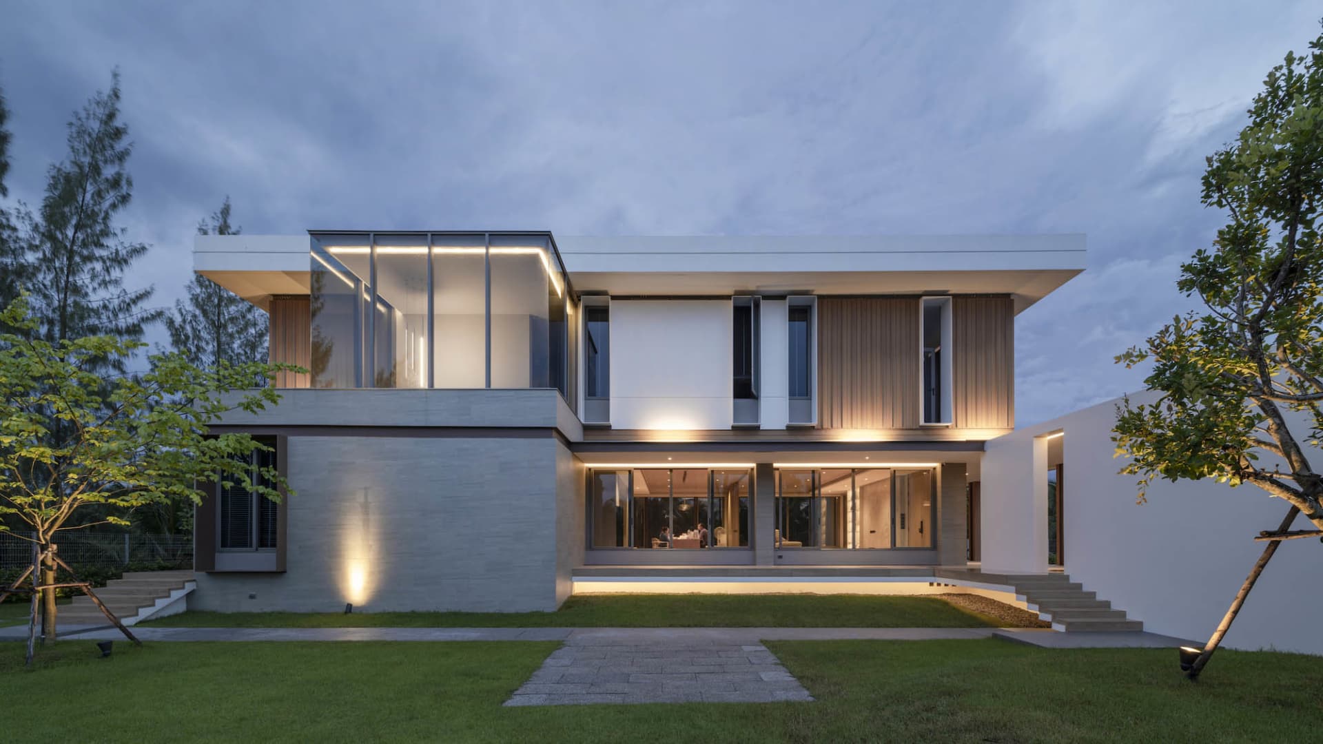 Modern house with glass walls, concrete base, and wooden accents.