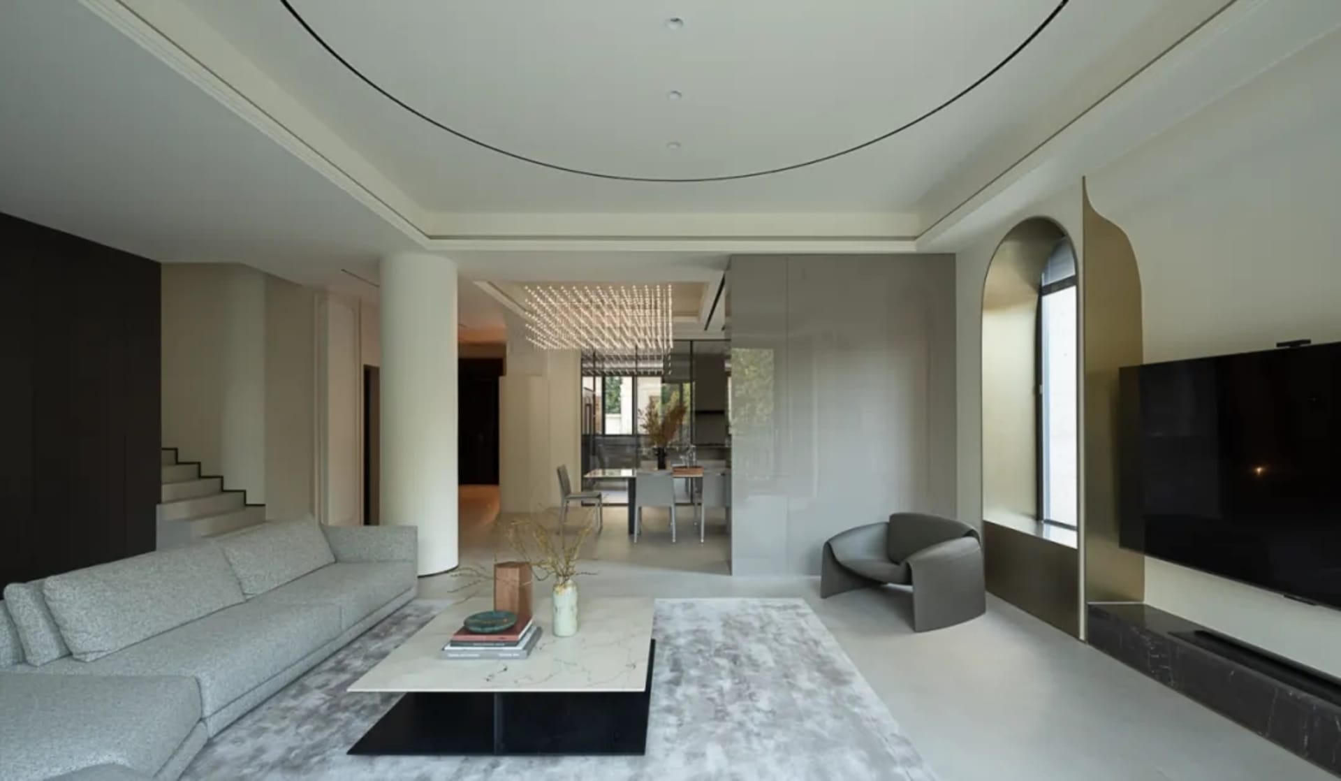 A modern living room with a minimalist design, featuring concrete walls, a white marble coffee table, and a ceiling light fix
