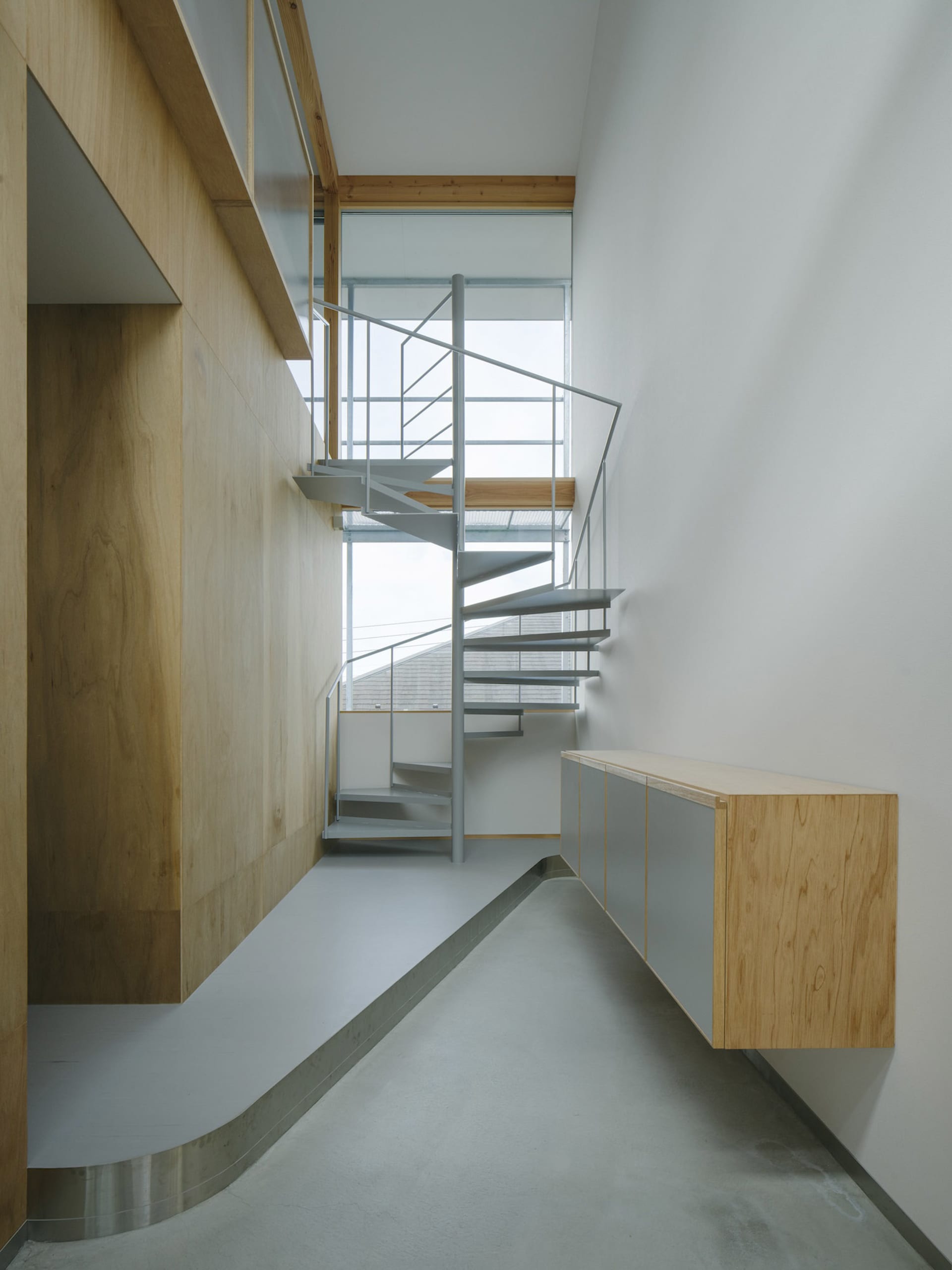 A minimalist interior with a metal staircase and wooden walls.